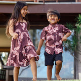 little girl wearing a long brown dress with tie sleeve with light pink lei awapuhi print and little boy wearing brown button-up with light pink lei awapuhi print