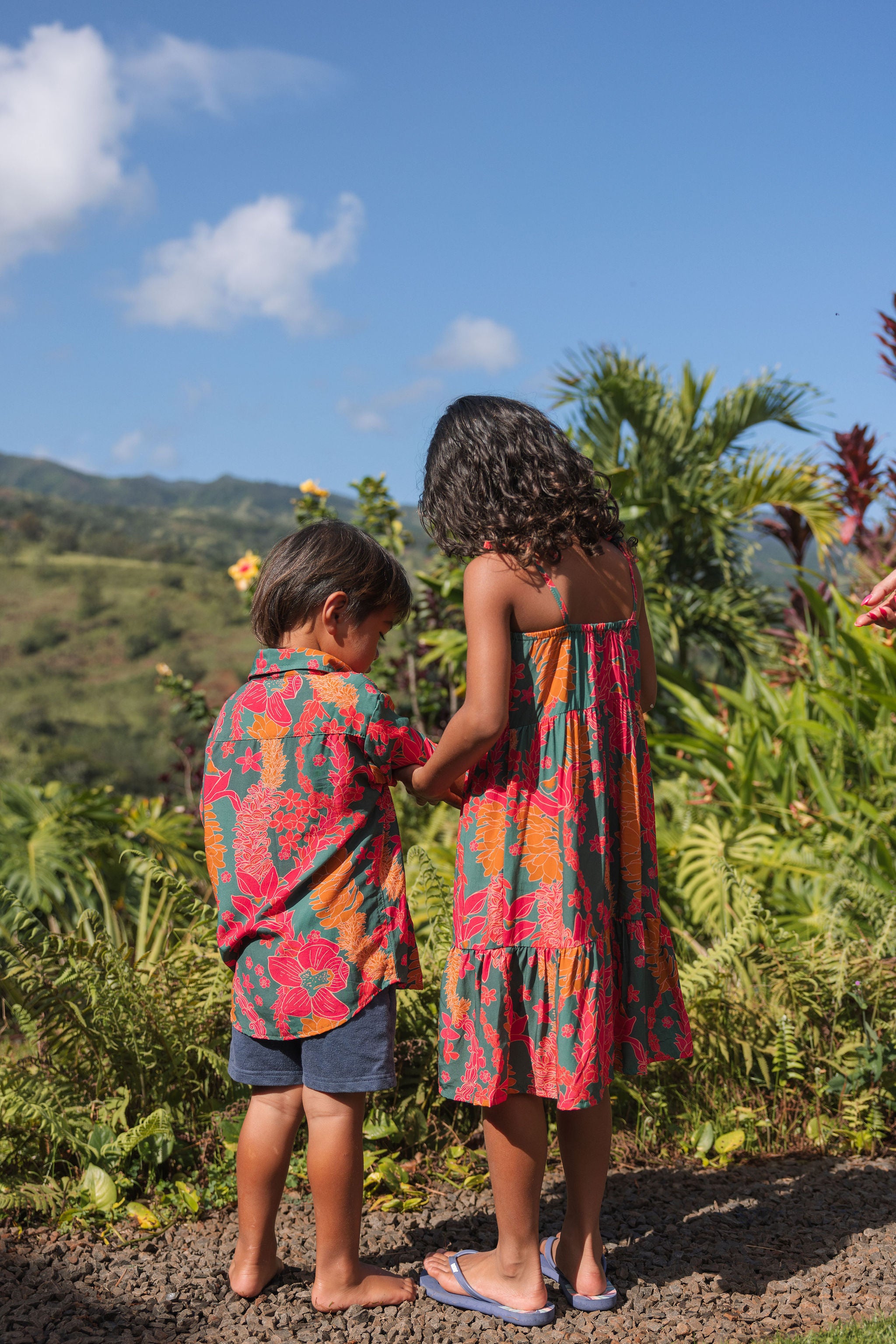girl with brown hair wearing a colorful dress with tropical lei print