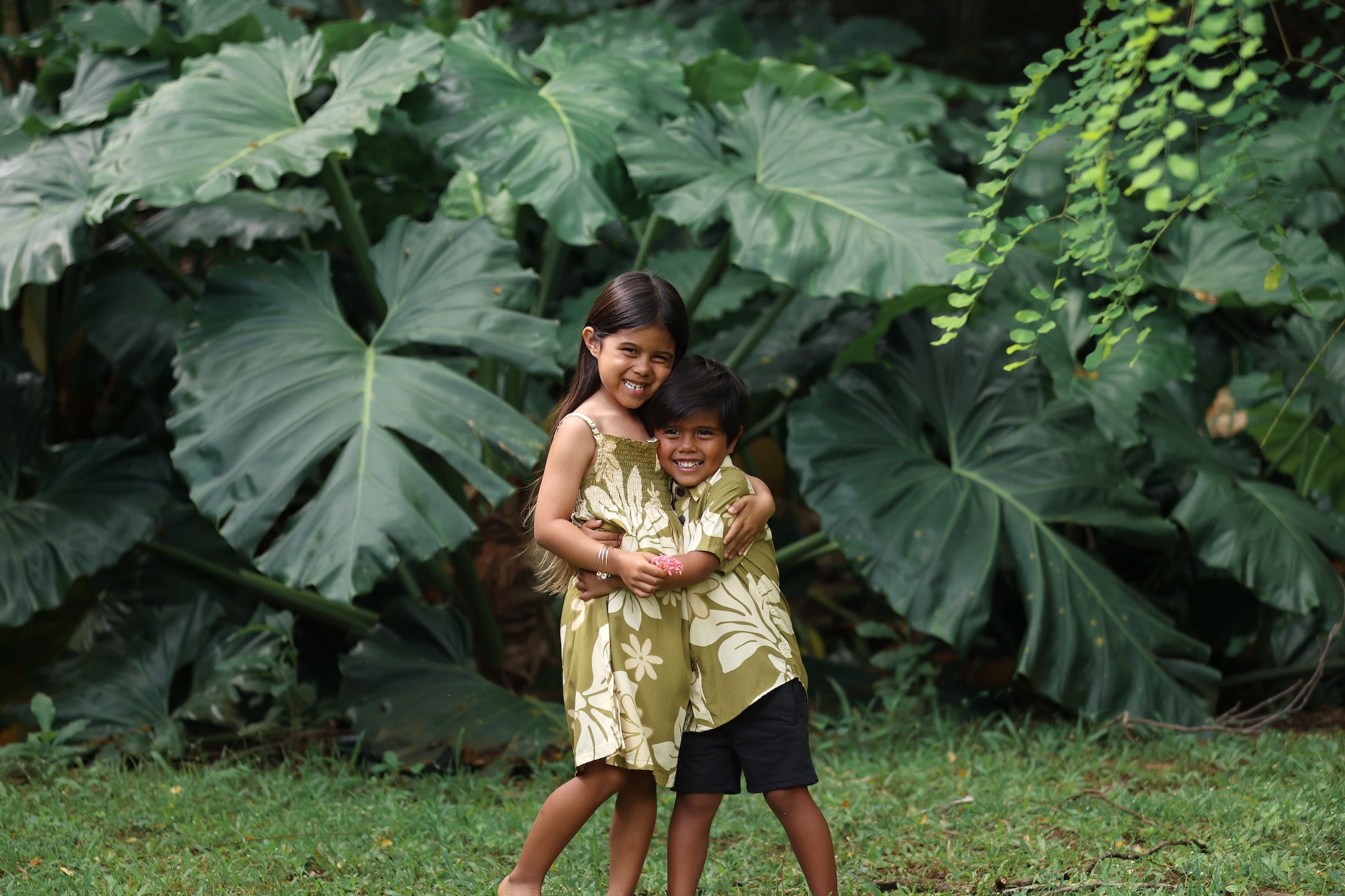 little girl wearing spaghetti strap dress in green print with naupaka pattern