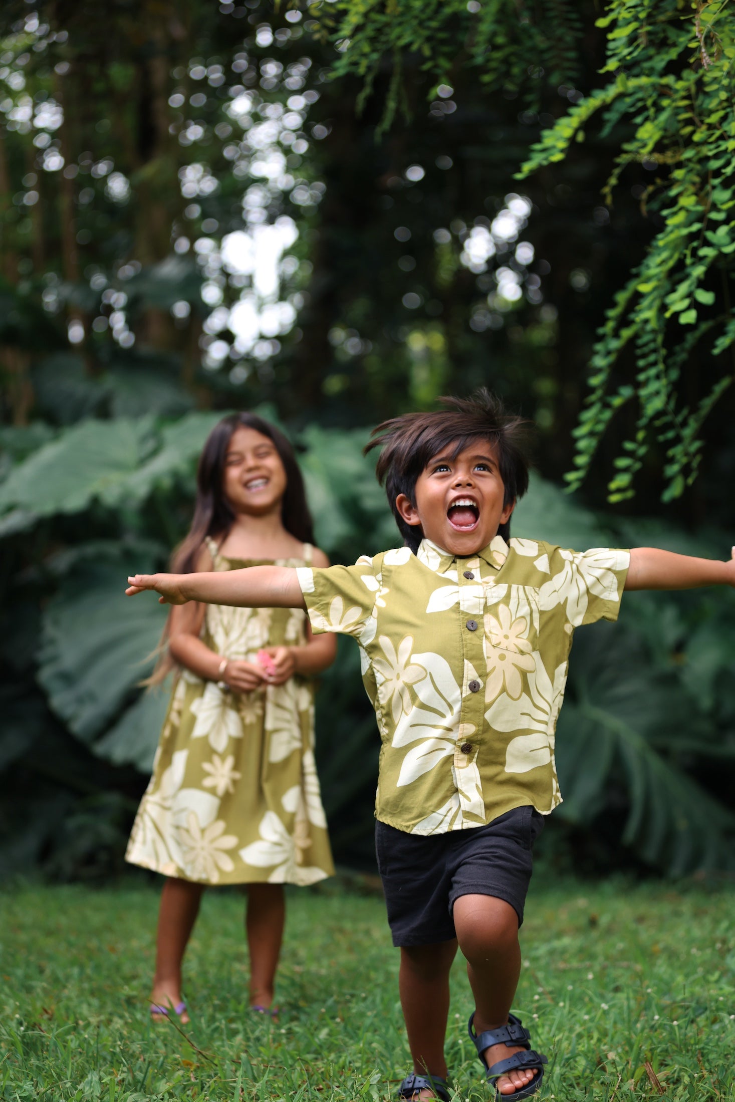 little boy wearing mini aloha button up shirt in green print and naupaka pattern