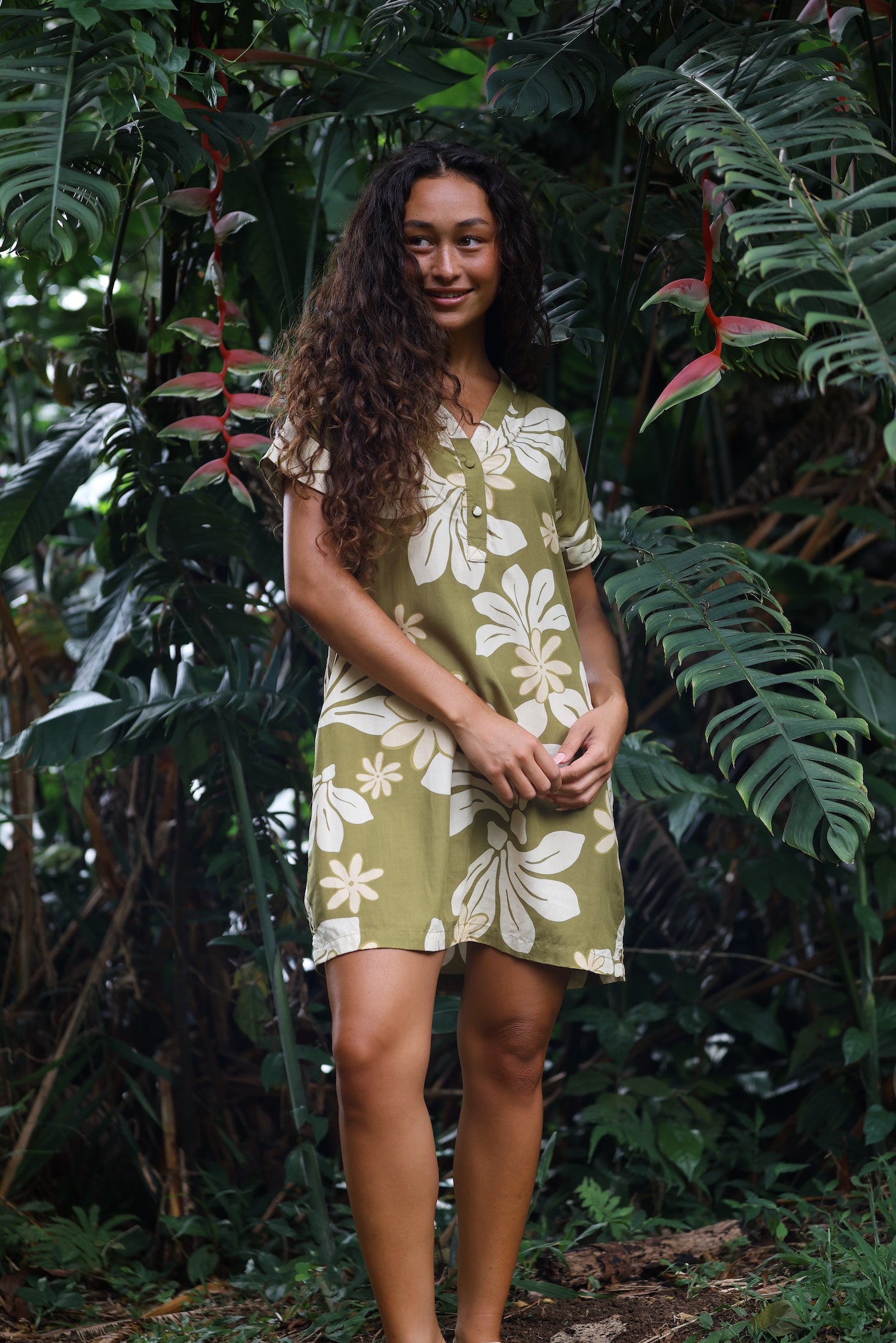 woman with brown hair wearing a shirt dress with v neck in green print with naupaka pattern