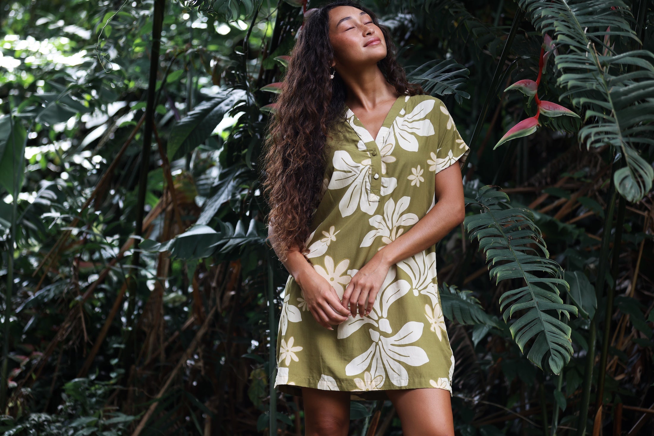 woman with brown hair wearing a shirt dress with v neck in green print with naupaka pattern
