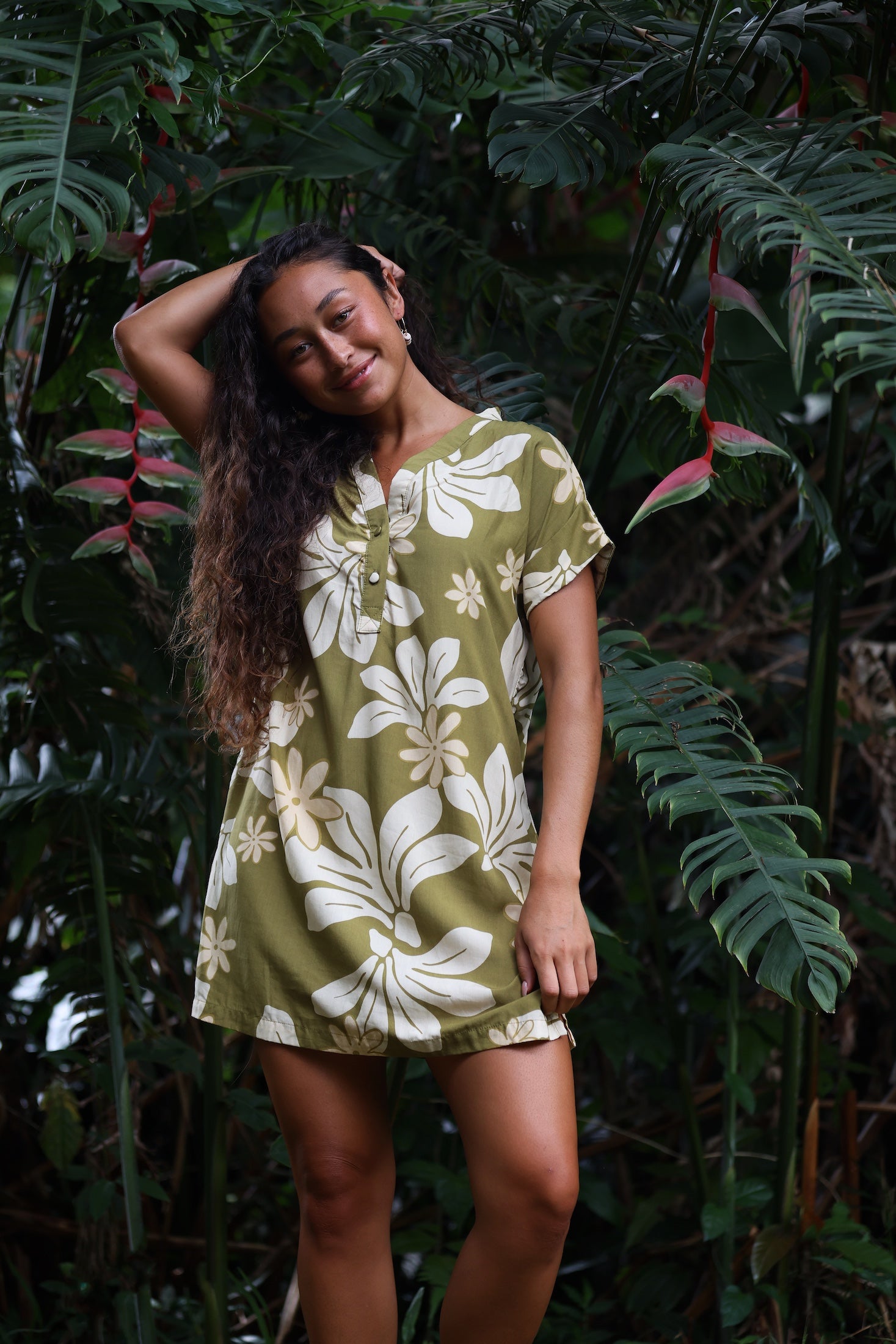 woman with brown hair wearing a shirt dress with v neck in green print with naupaka pattern
