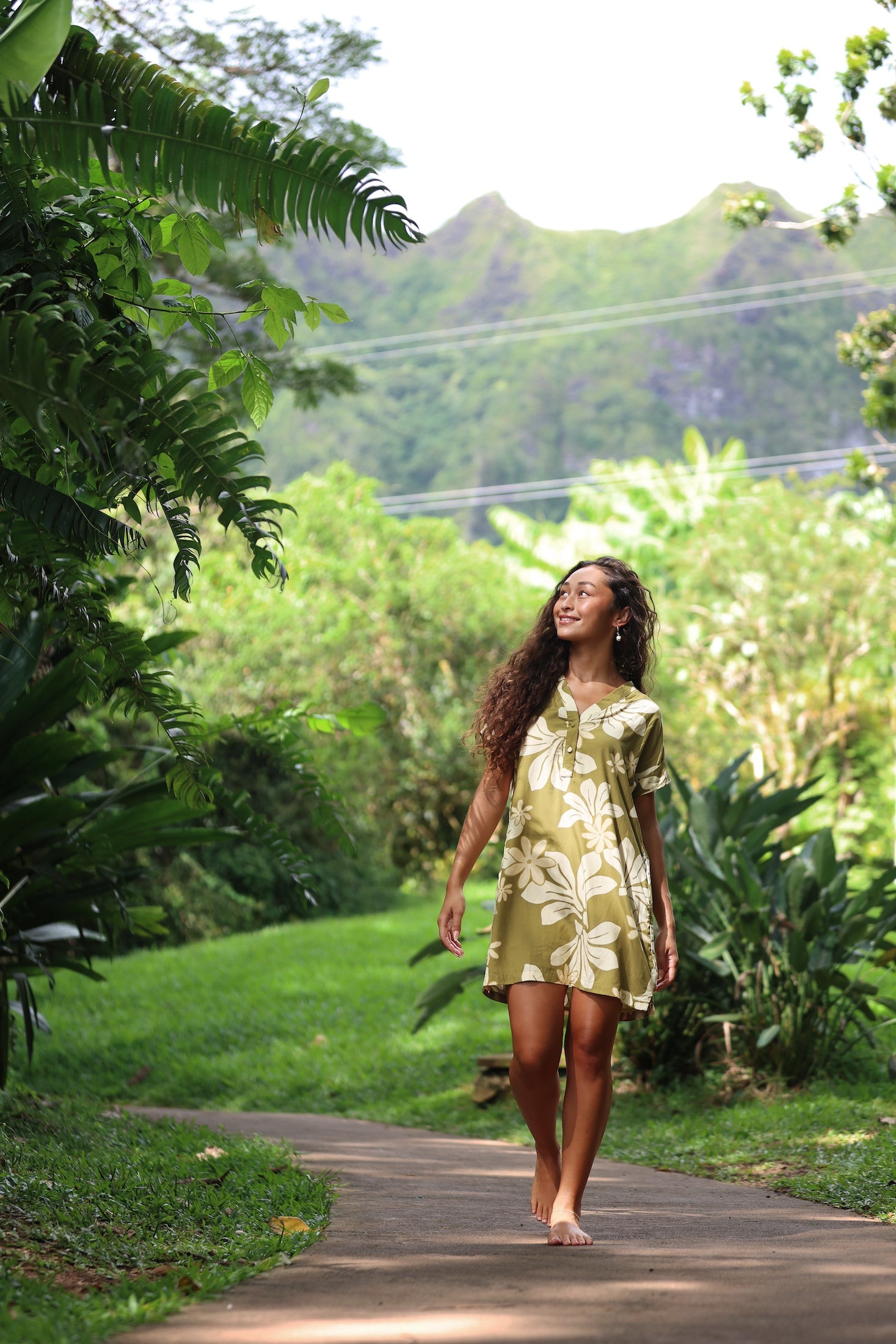 woman with brown hair wearing a shirt dress with v neck in green print with naupaka pattern
