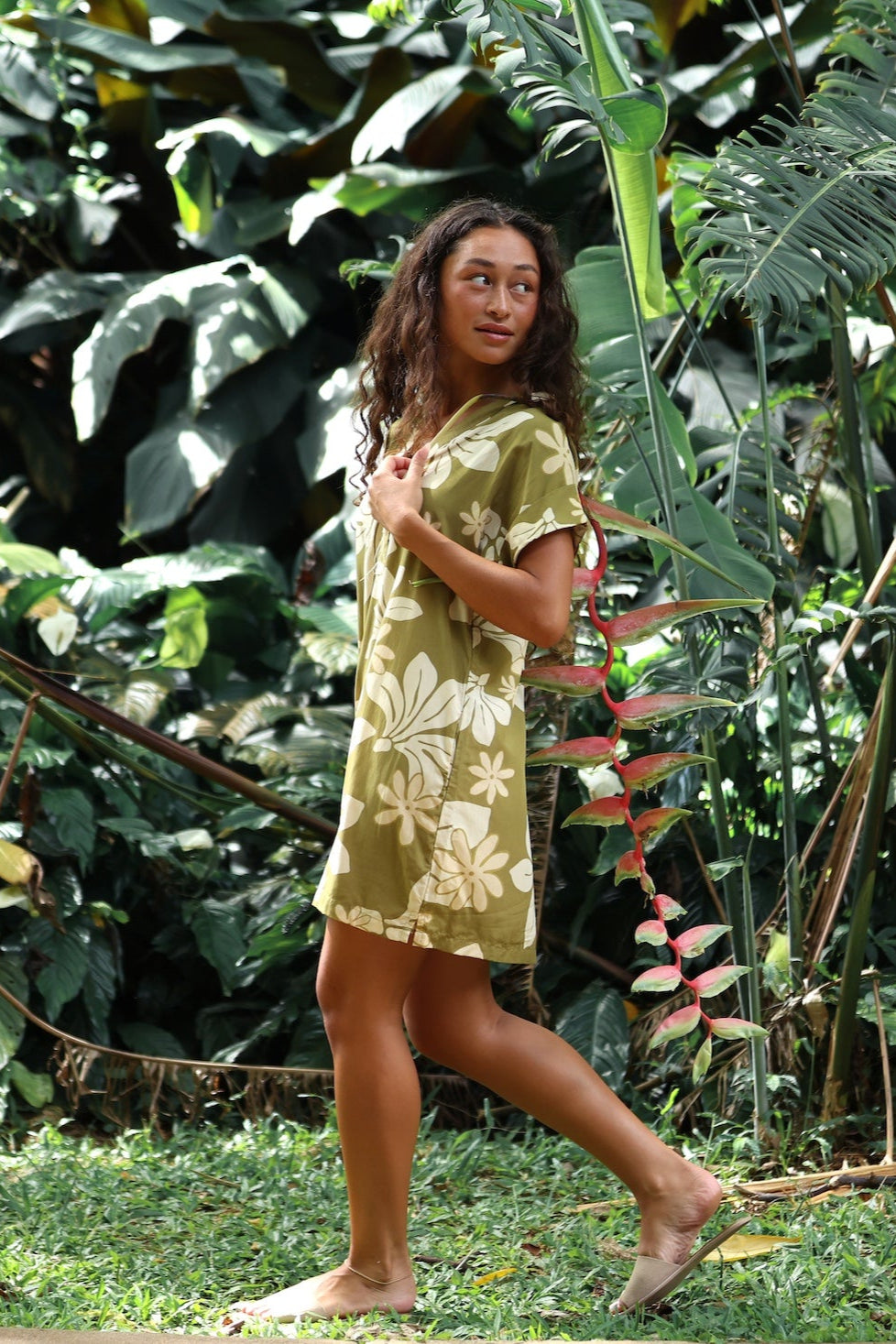 woman with brown hair wearing a shirt dress with v neck in green print with naupaka pattern