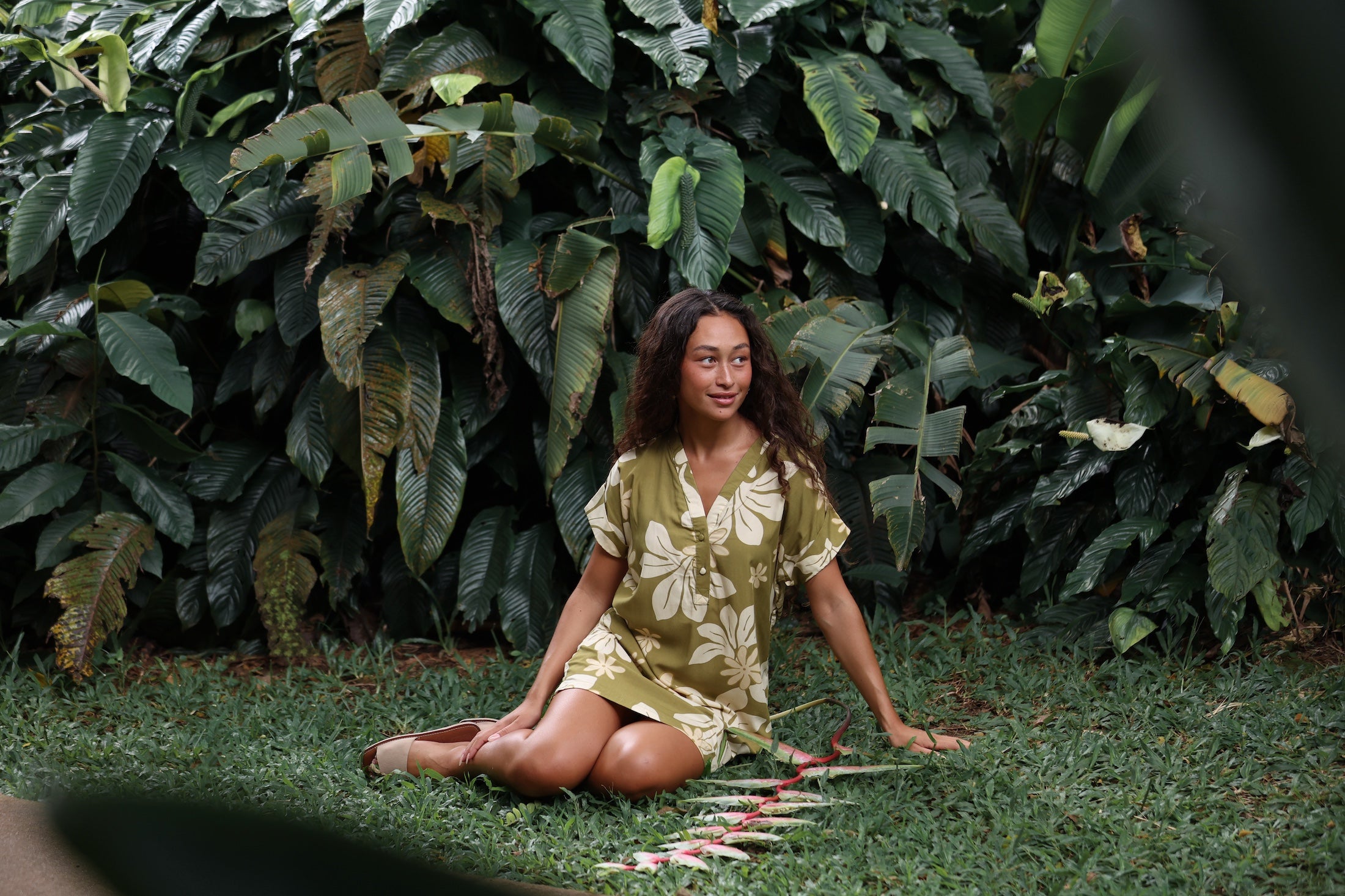 woman with brown hair wearing a shirt dress with v neck in green print with naupaka pattern