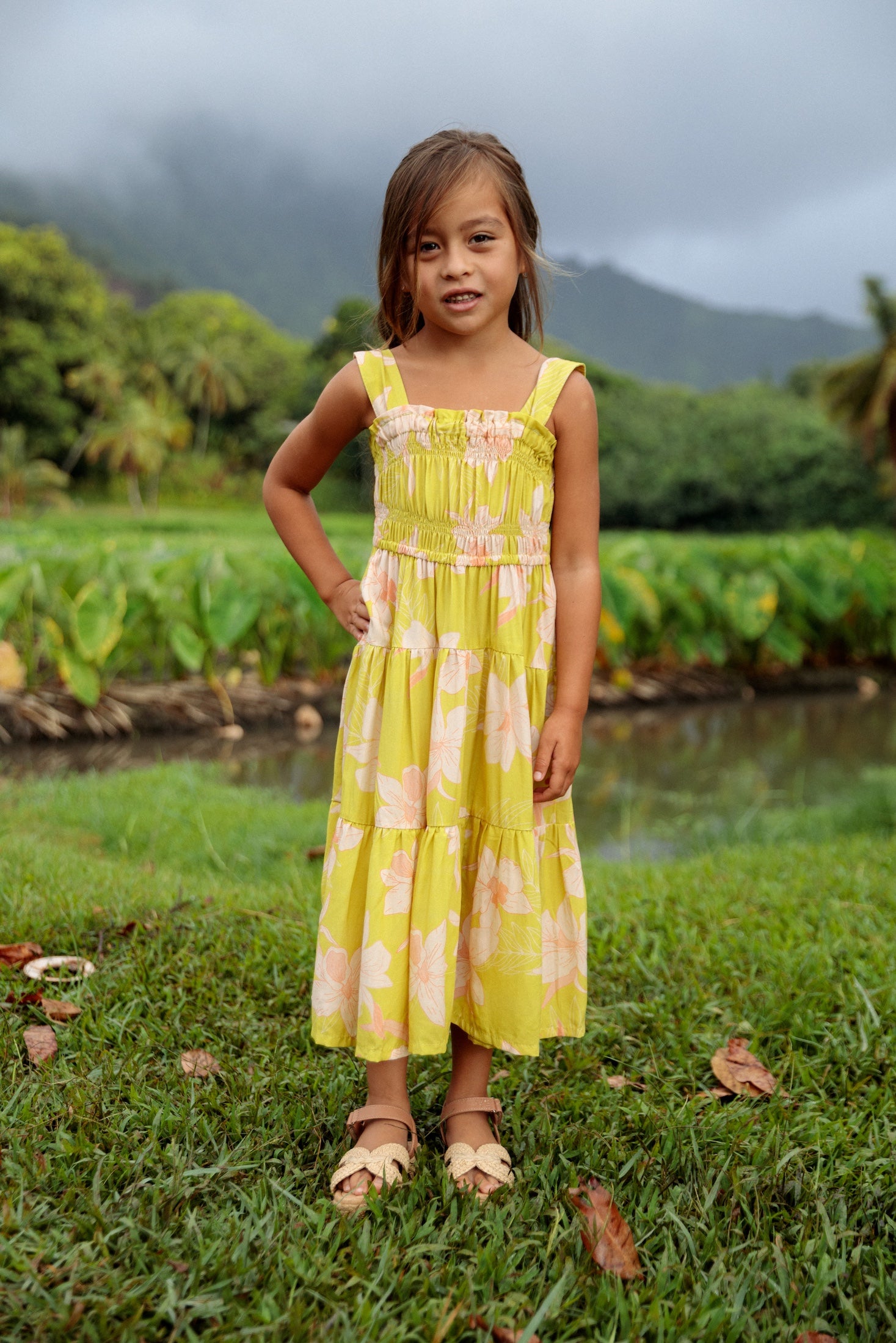 little girl wearing long flowy dress in bright green with orchid pattern