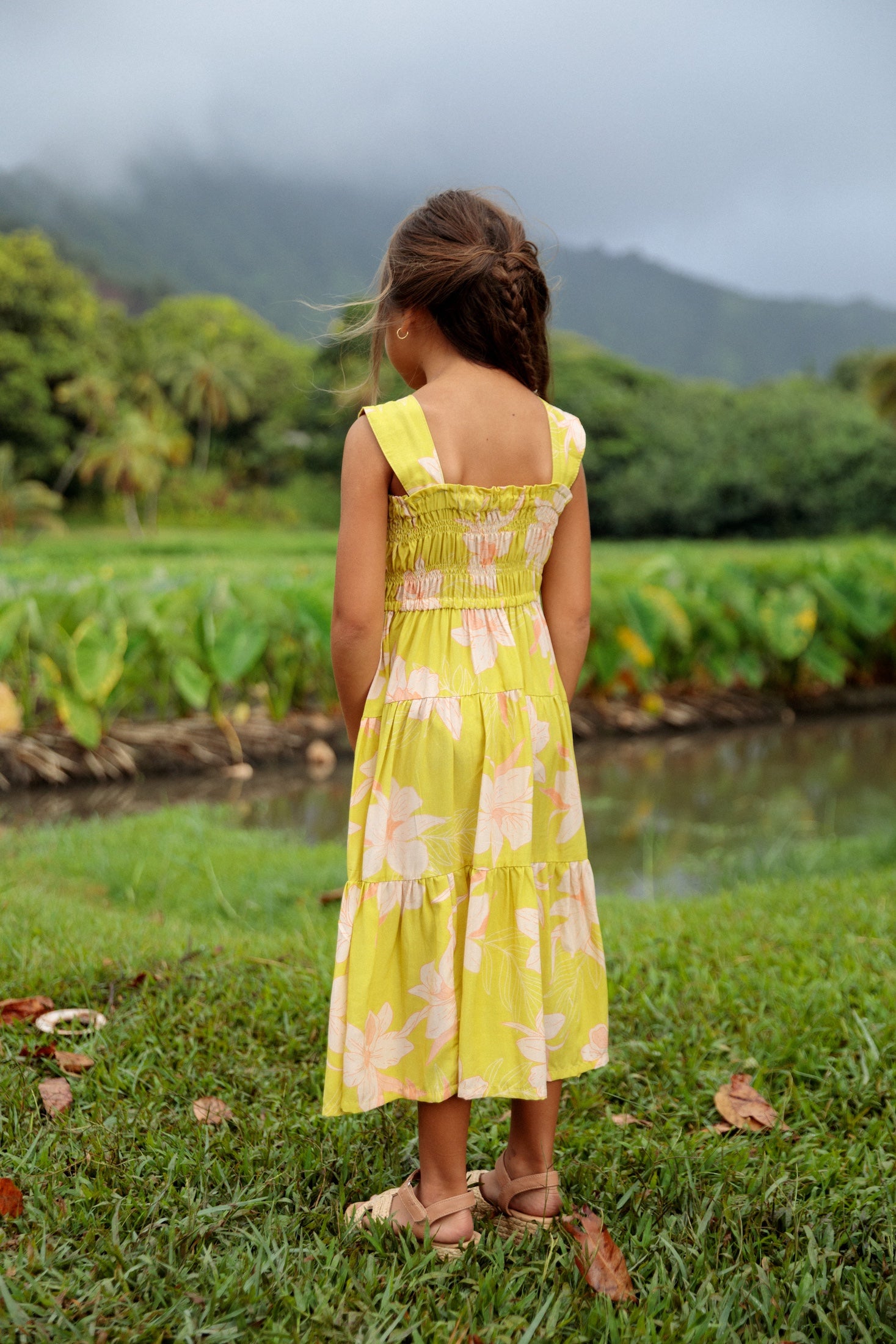 little girl wearing long flowy dress in bright green with orchid pattern
