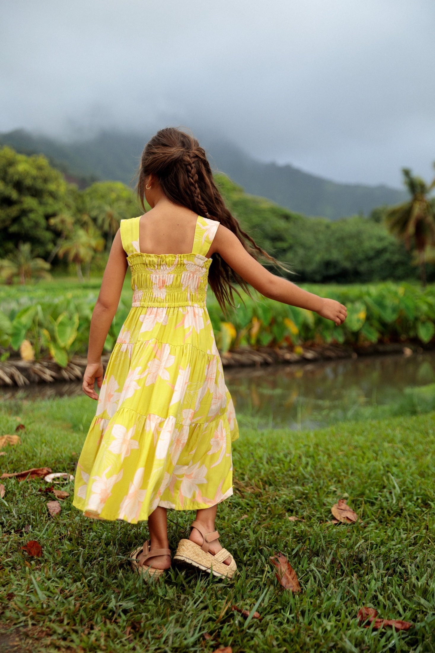 little girl wearing long flowy dress in bright green with orchid pattern