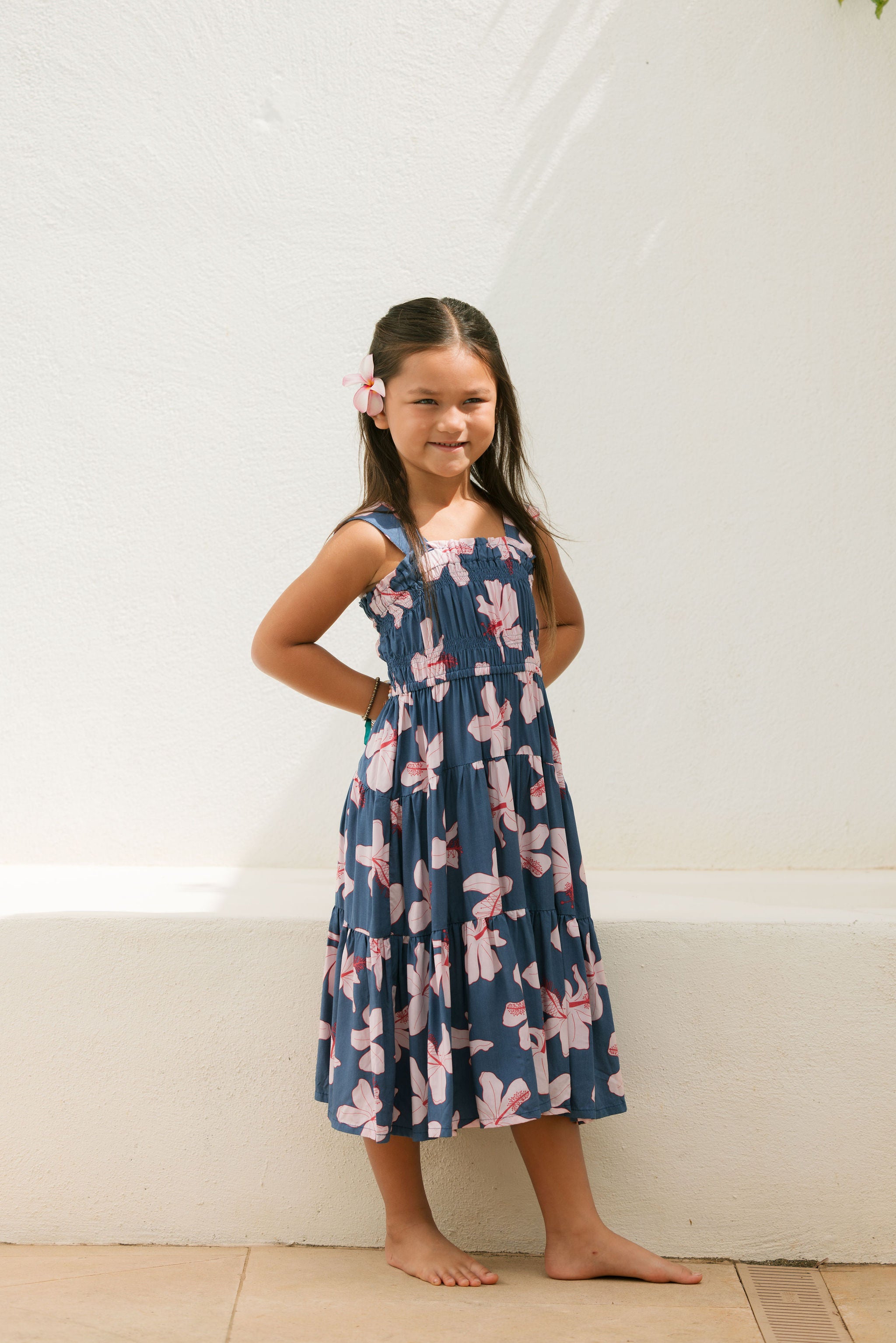 little girl wearing a tiered maxi dress in navy and pink hibiscus print.