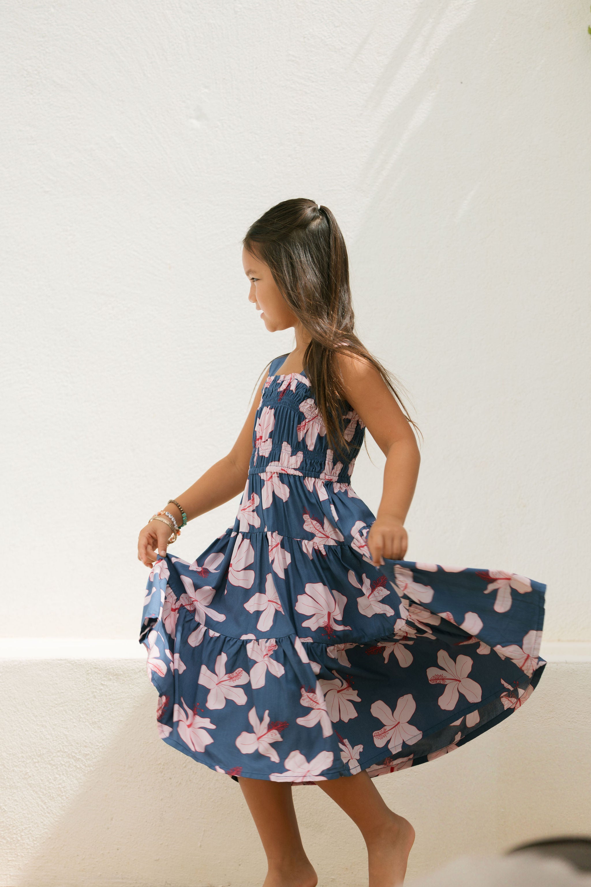 little girl wearing a tiered maxi dress in navy and pink hibiscus print.