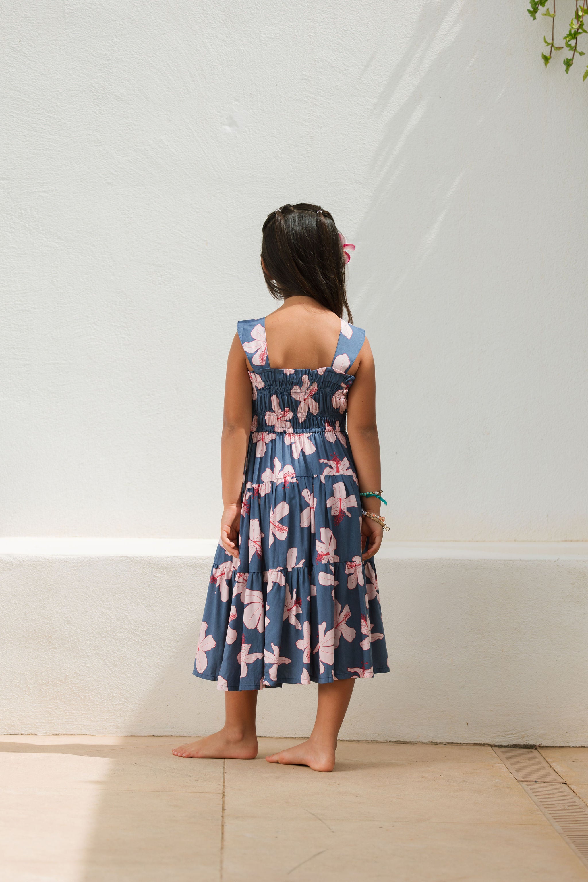 little girl wearing a tiered maxi dress in navy and pink hibiscus print.