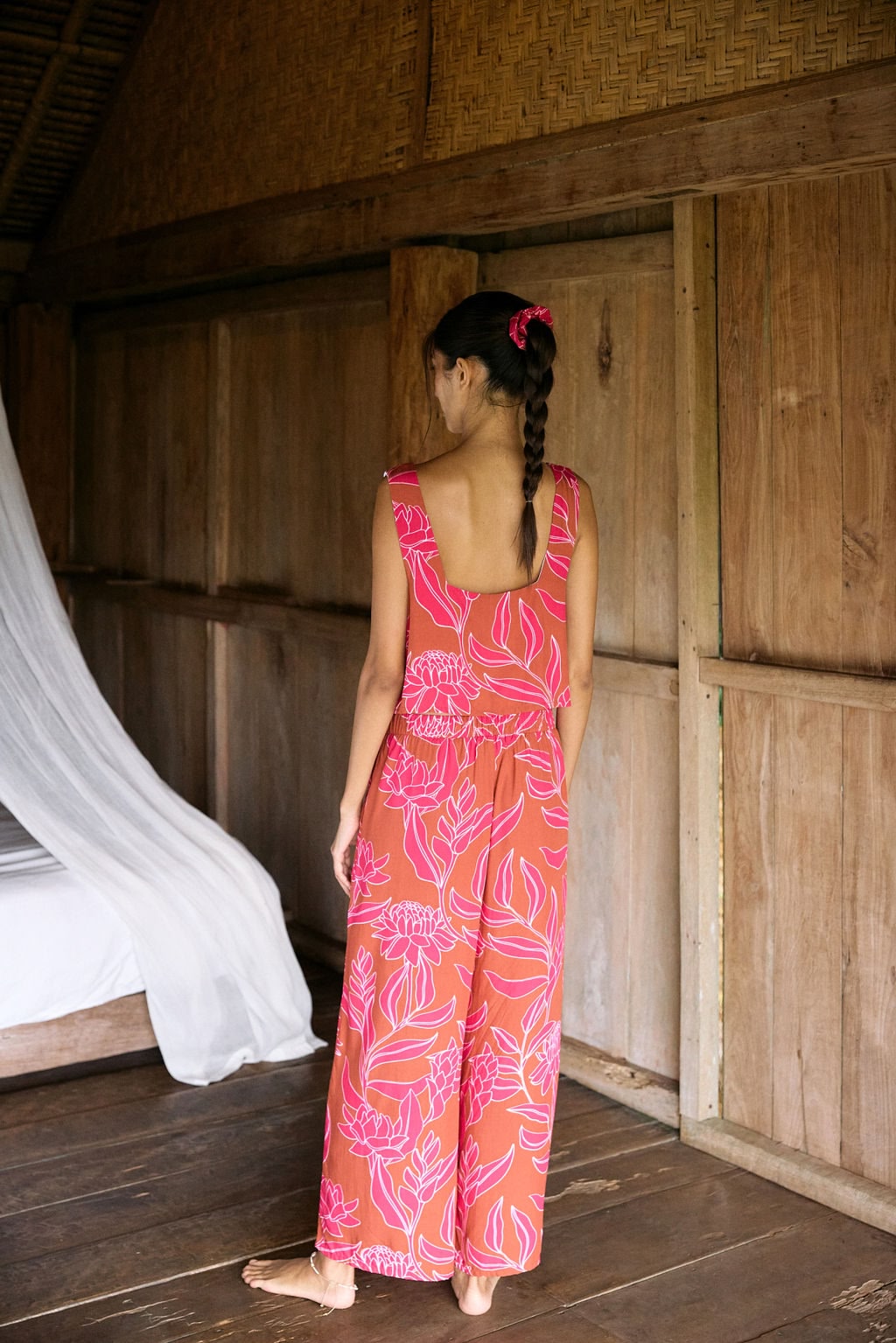 A woman with dark hair wears a YIREH wide legged pant with elastic waistband. It is the Elodi Pant in the Garden 'Awapuhi print.