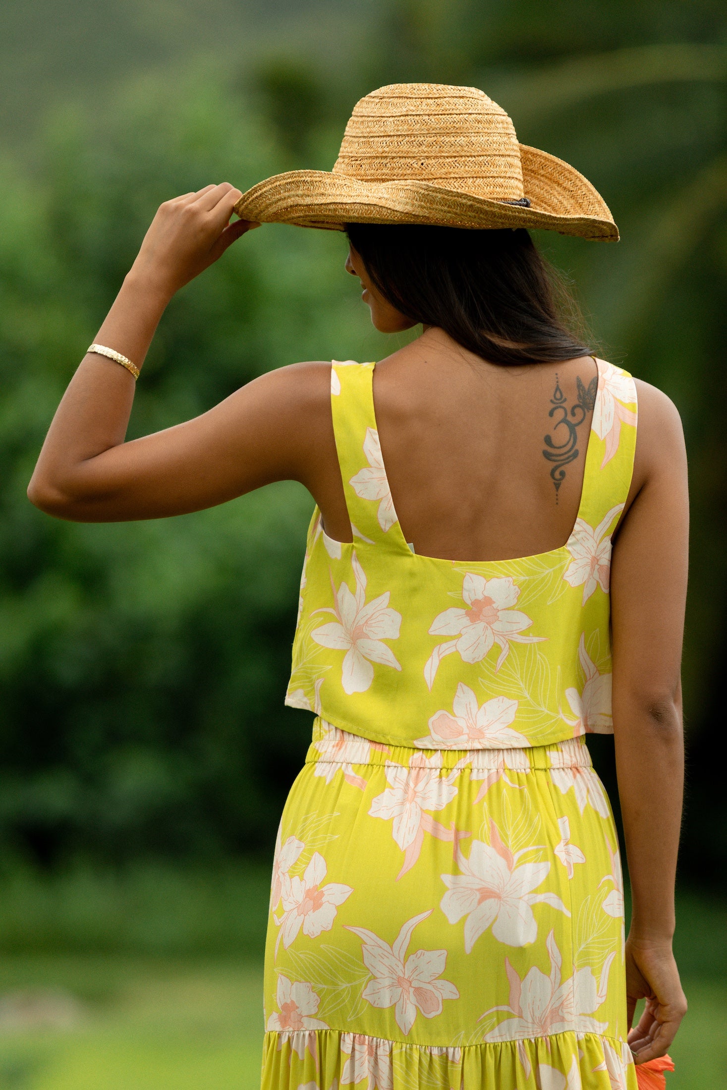 woman wearing a bright green orchid print cropped top with matching maxi skirt