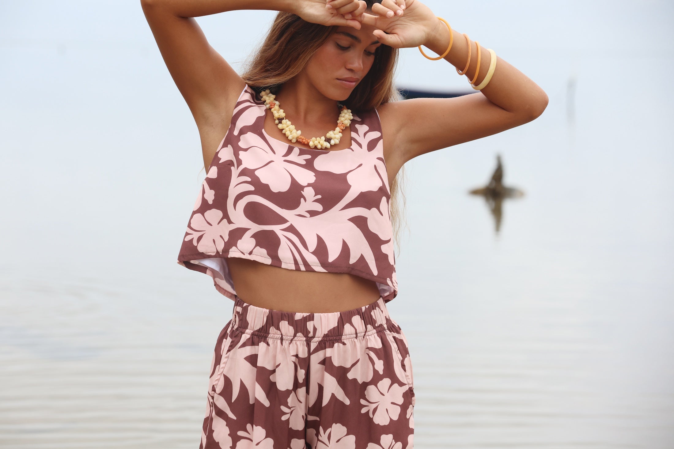 Woman with brown hair wearing a matching top and shorts set in blush and brown hibiscus print. It is the Naia Top and Millie Shorts.