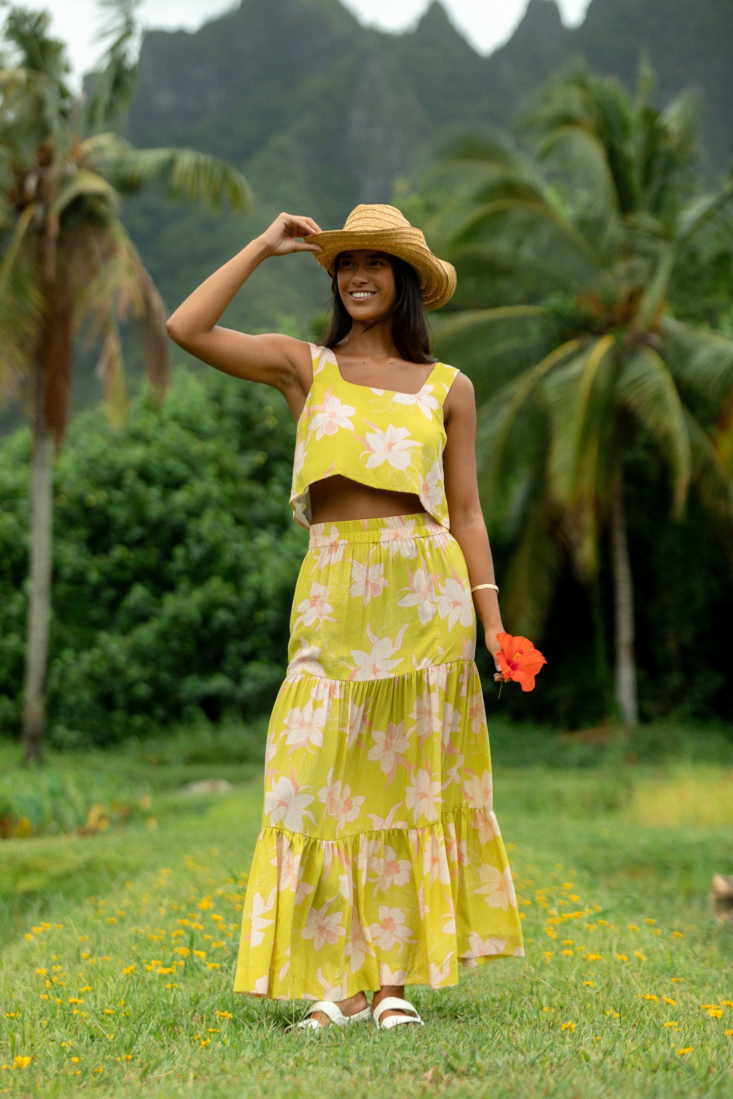 woman wearing a bright green orchid print cropped top with matching maxi skirt