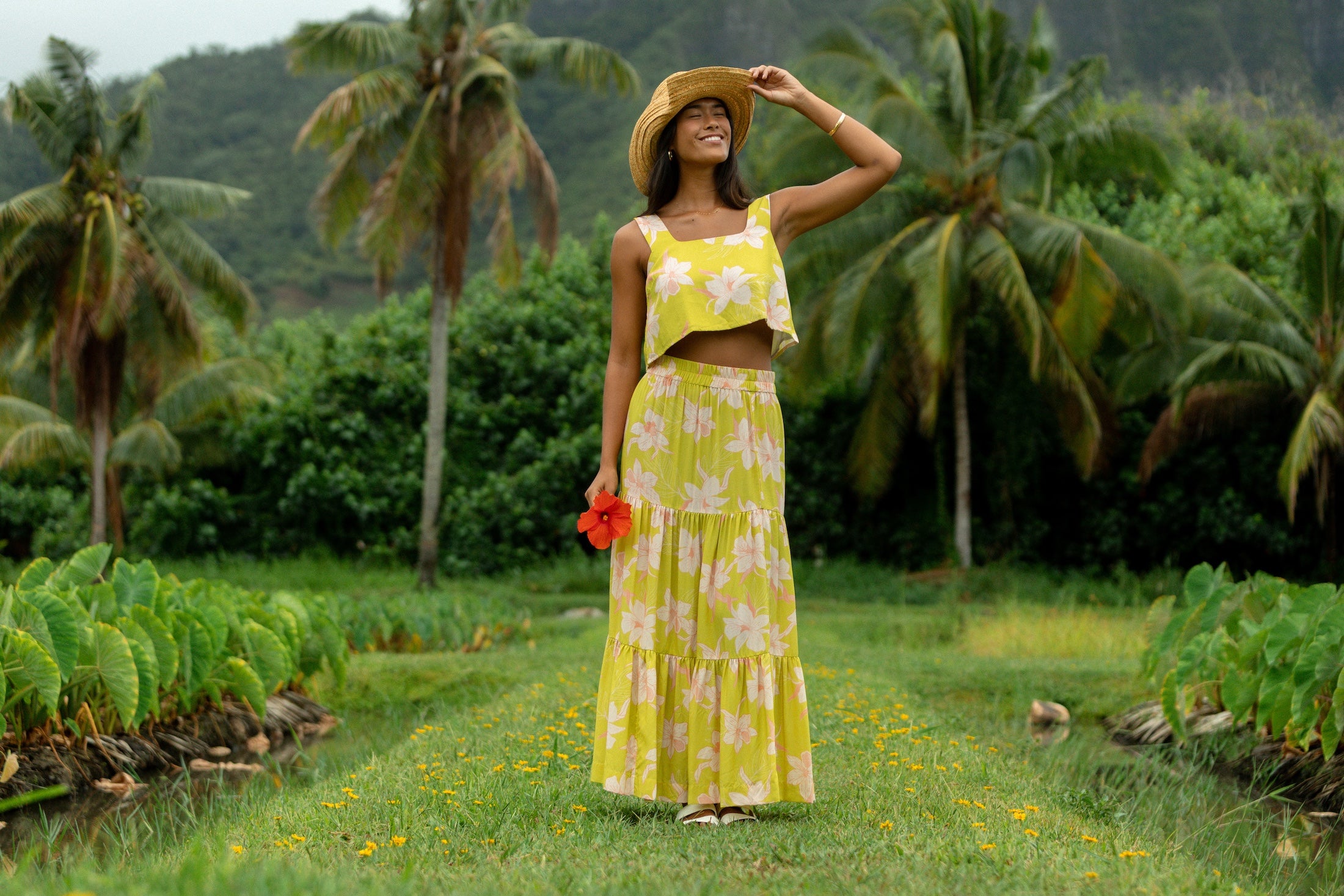 woman wearing a bright green orchid print cropped top with matching maxi skirt