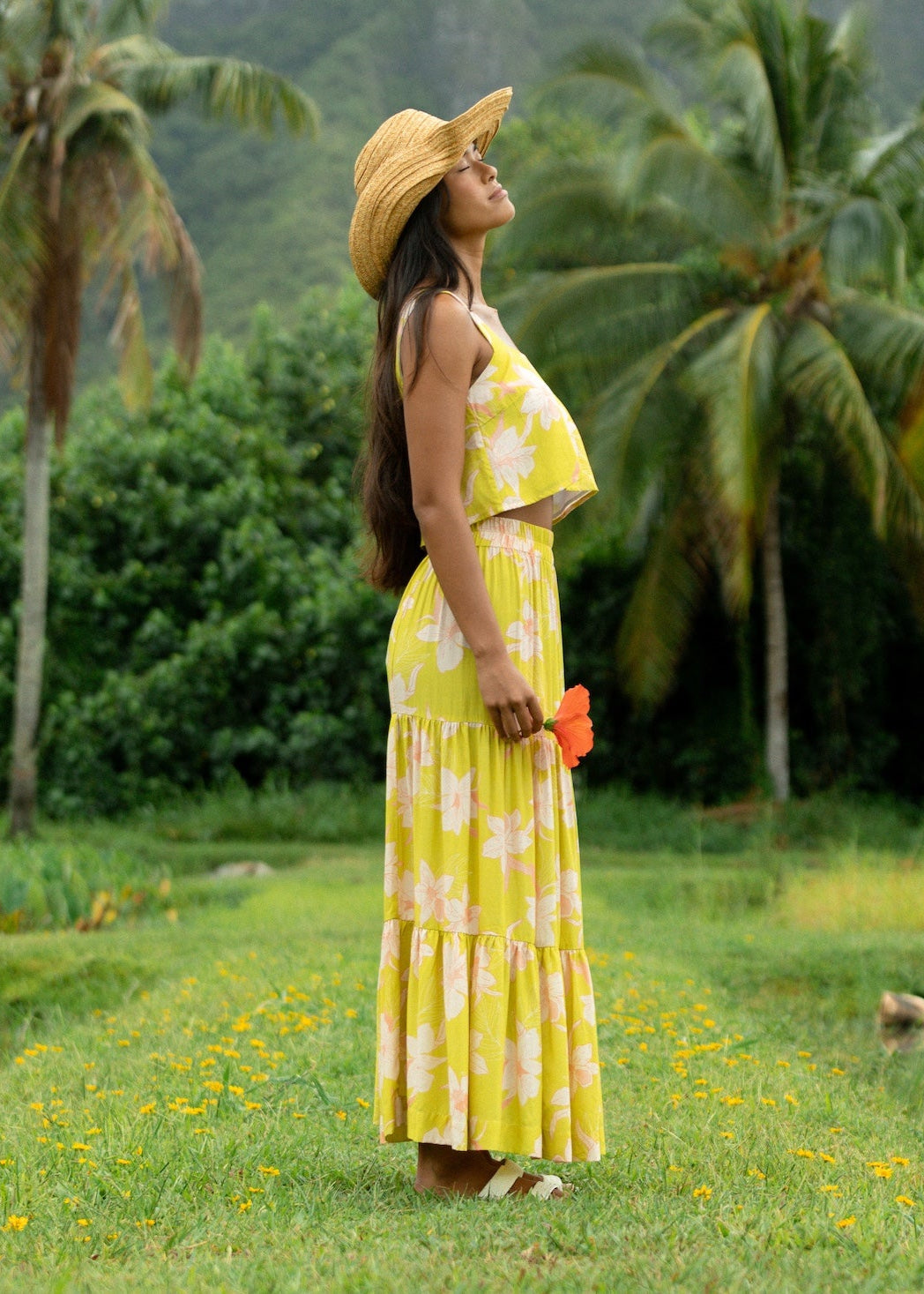 woman wearing a bright green orchid print cropped top with matching maxi skirt