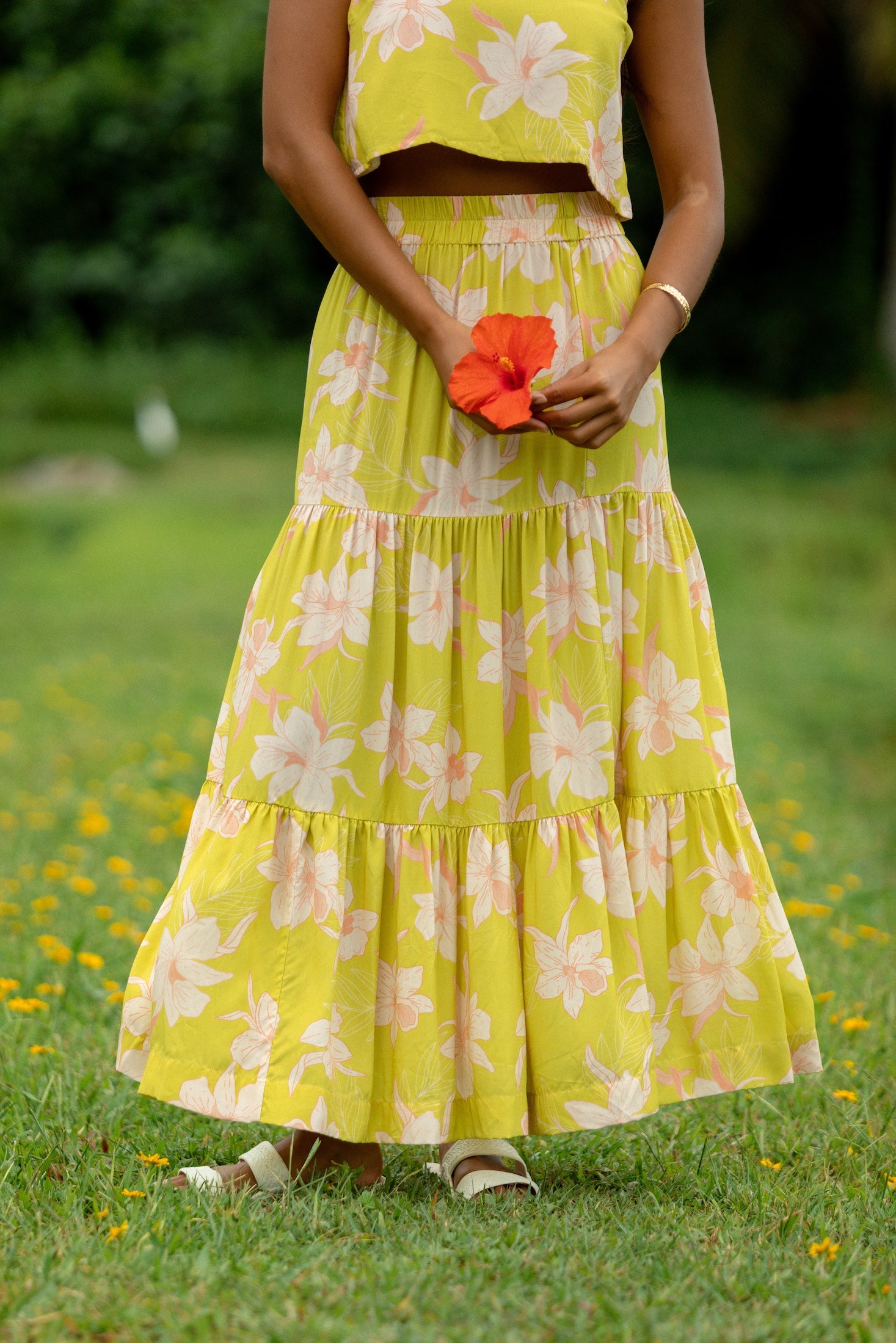 woman wearing a bright green orchid print maxi skirt with matching top