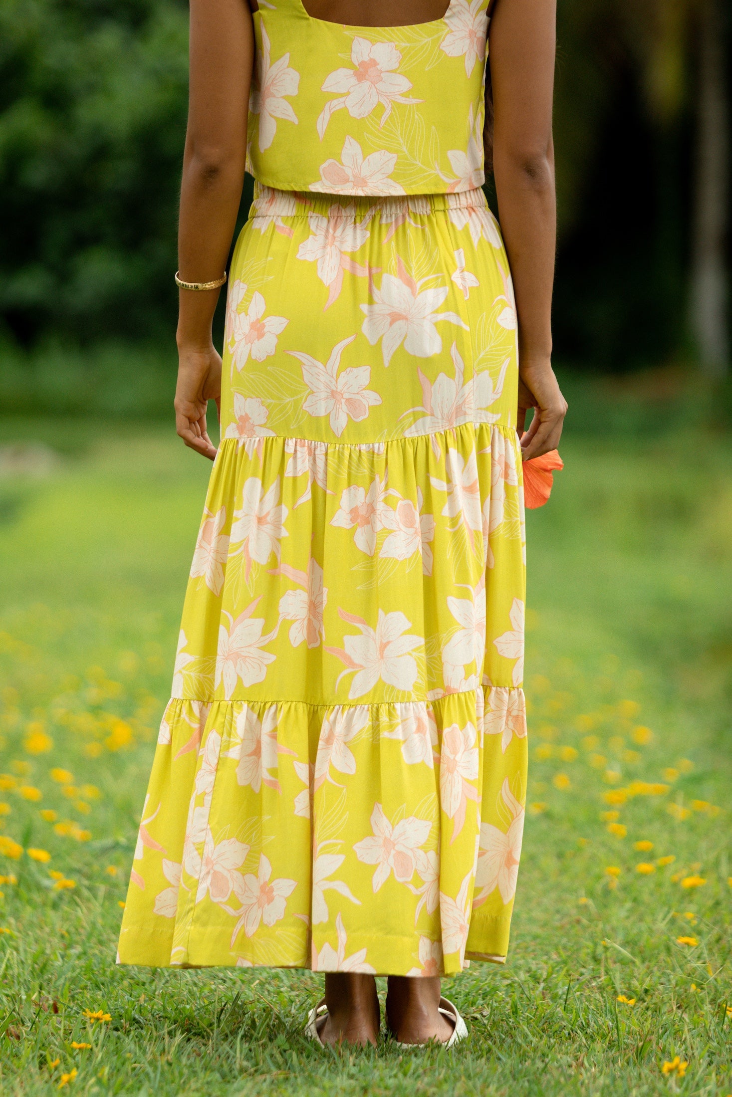 woman wearing a bright green orchid print maxi skirt with matching top
