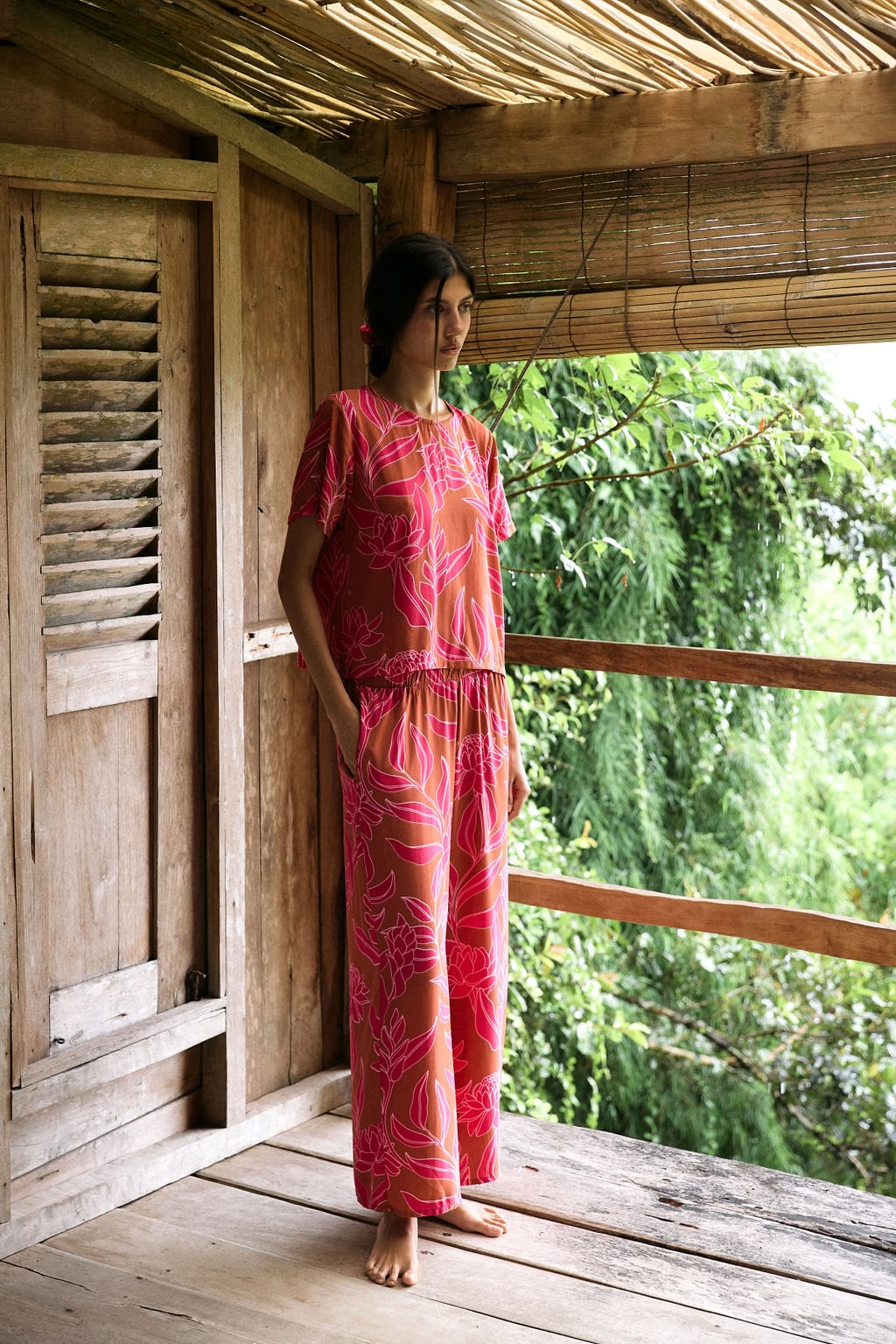 A woman with dark hair wears a YIREH wide legged pant with elastic waistband. It is the Elodi Pant in the Garden 'Awapuhi print.