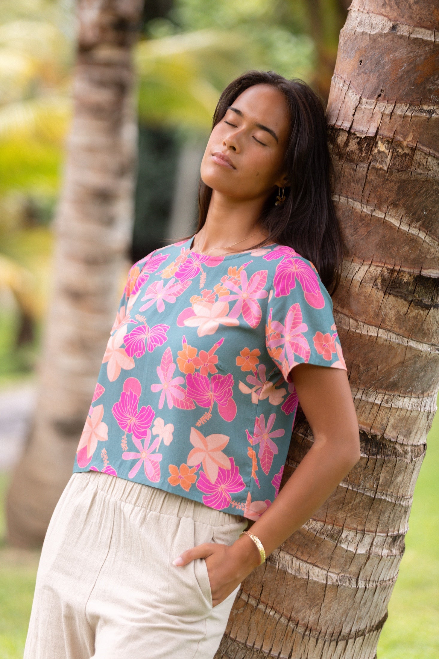 woman with brown hair wearing a teal t-shirt top with orange and pink foral print