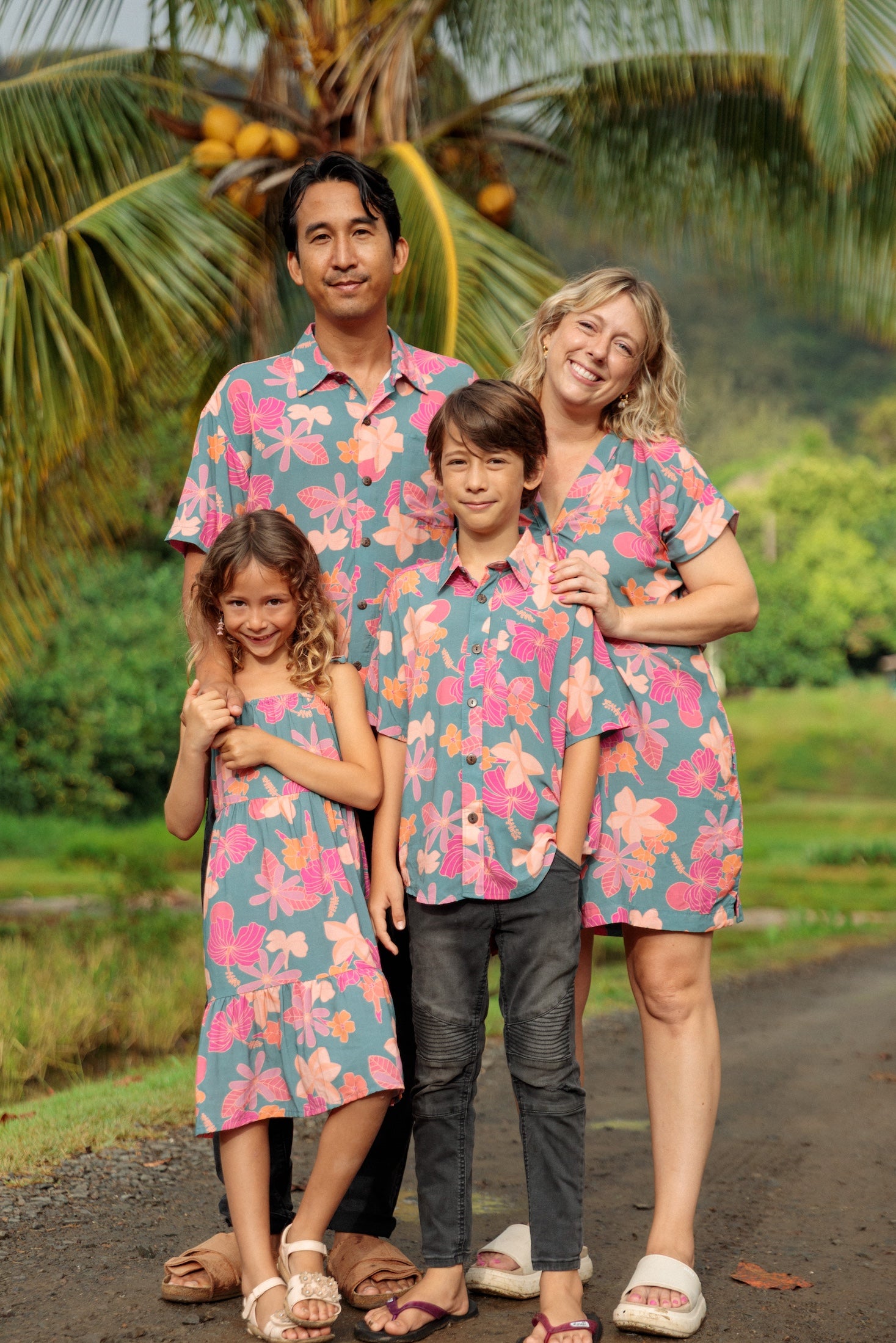 family wearing matching teal aloha wear with floral print