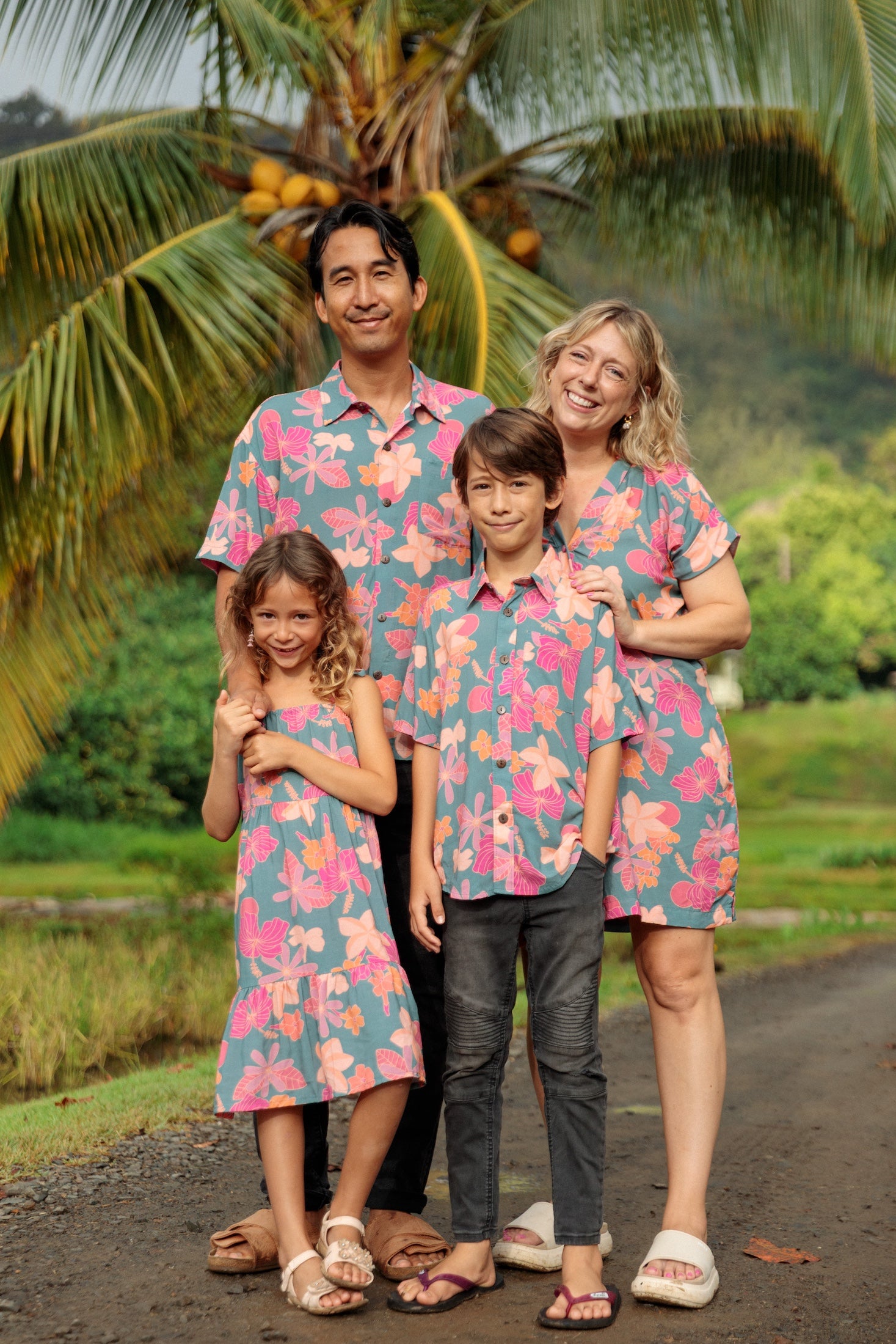 family wearing matching teal aloha wear with floral print