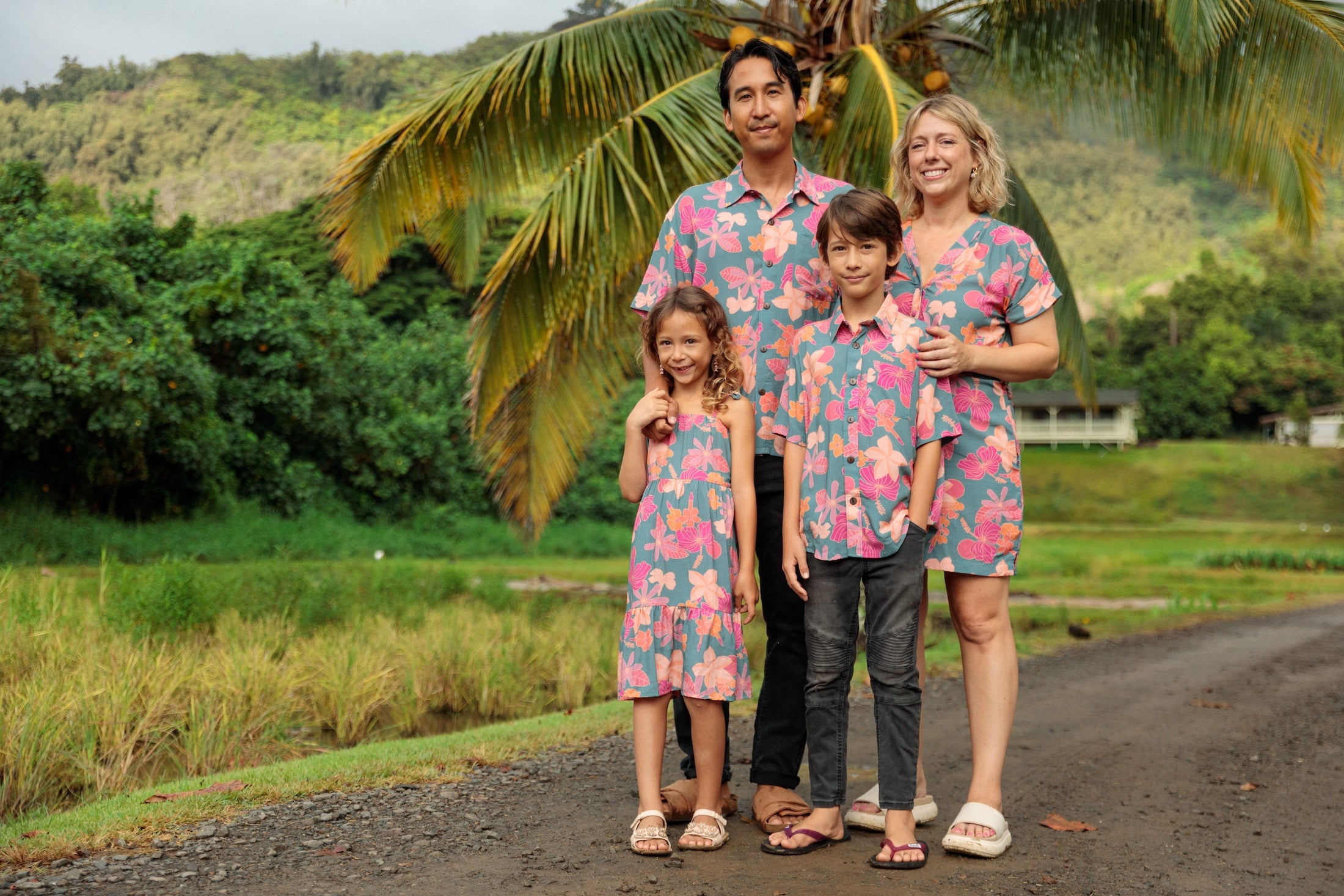 family wearing matching teal aloha wear with floral print