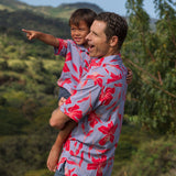 man with brown hair wearing a button up aloha shirt with periwinkle background and bright red hibiscus print.