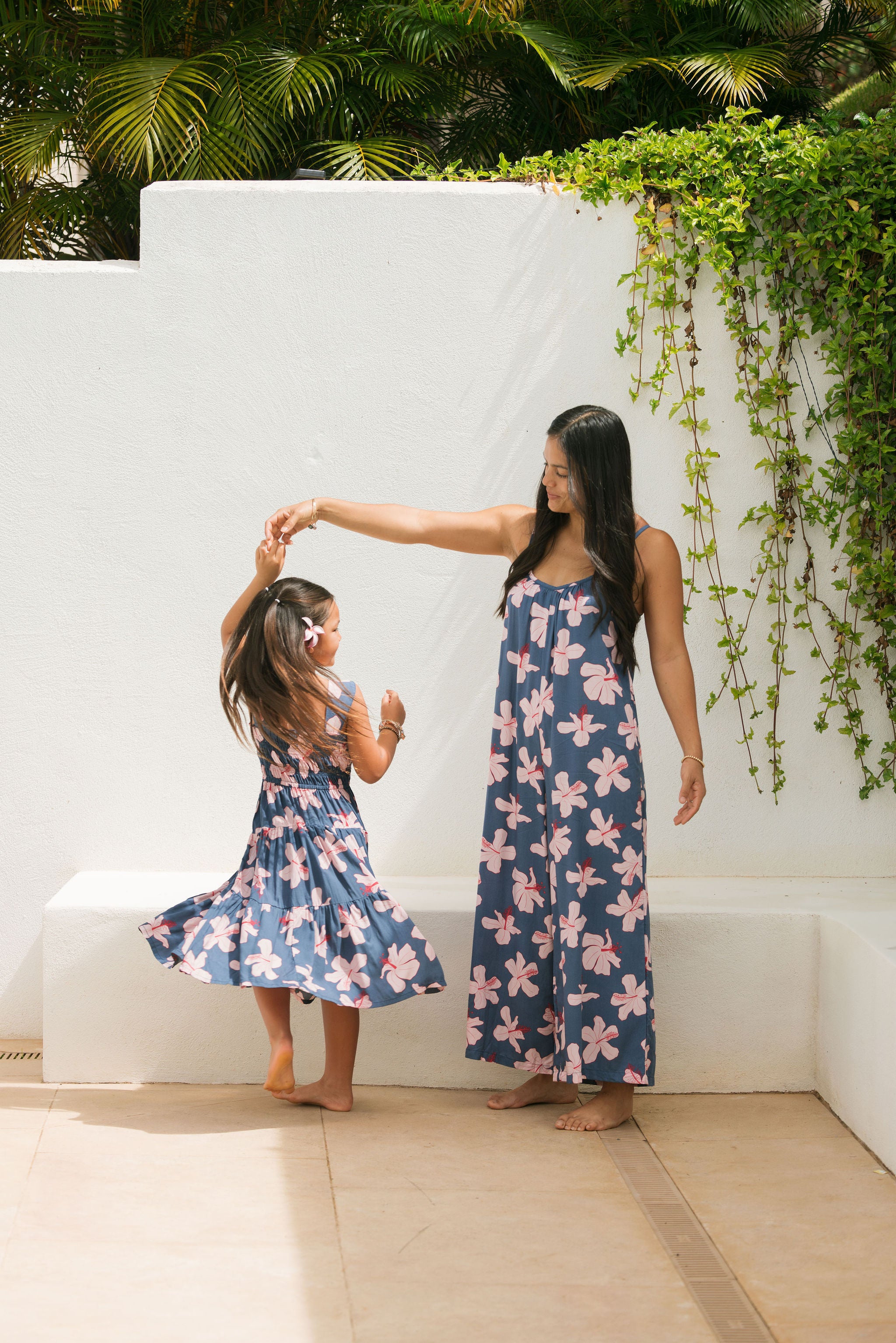 little girl wearing a tiered maxi dress in navy and pink hibiscus print.