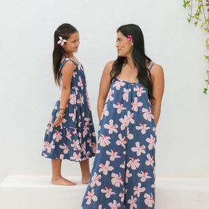 little girl wearing a tiered maxi dress in navy and pink hibiscus print.