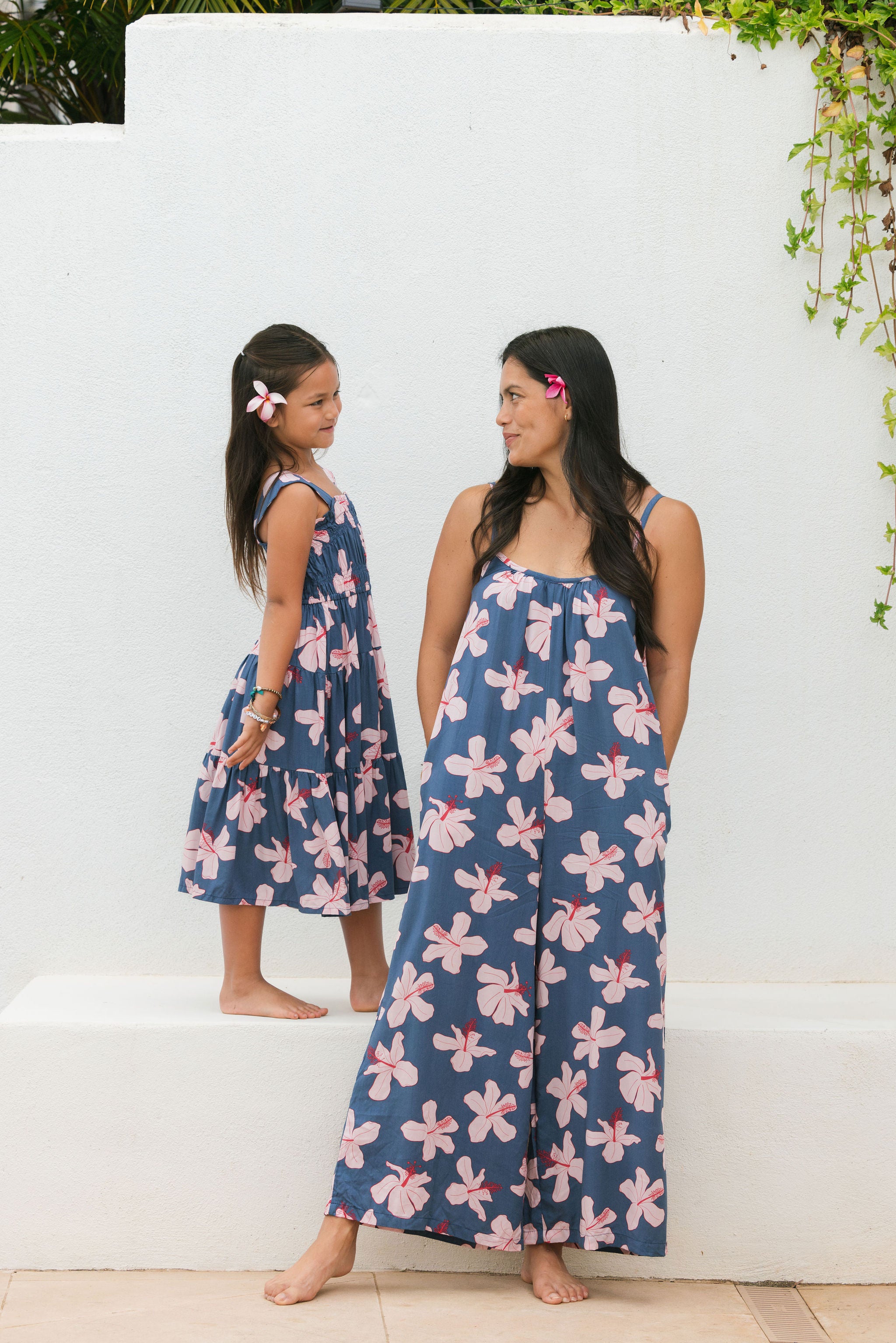 little girl wearing a tiered maxi dress in navy and pink hibiscus print.