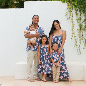 little boy wearing button up aloha shirt in navy and pink hibiscus print.