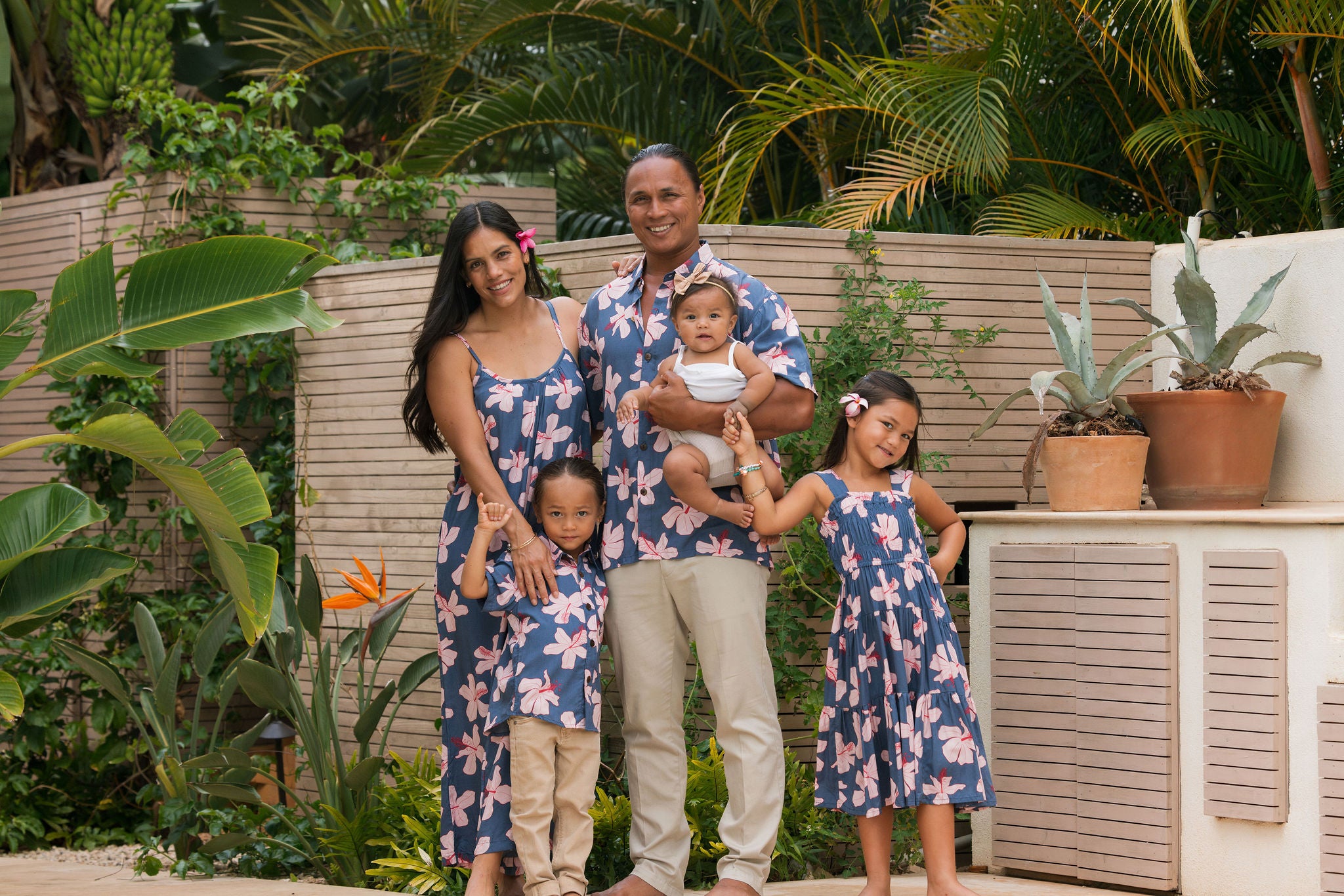 man wearing button up aloha shirt in navy and pink hibiscus print.