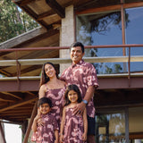 man wearing brown aloha shirt with pink lei awapuhi print