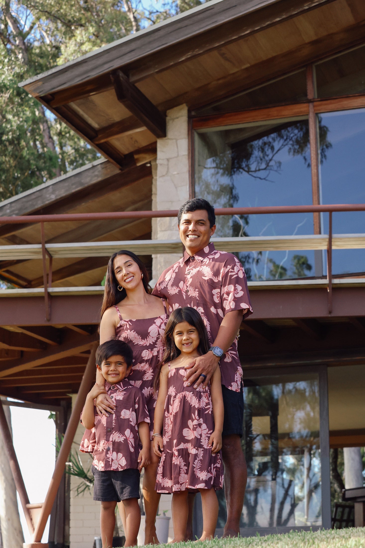 man wearing brown aloha shirt with pink lei awapuhi print