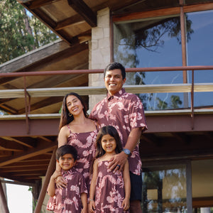 man wearing brown aloha shirt with pink lei awapuhi print