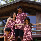 man wearing brown aloha shirt with pink lei awapuhi print