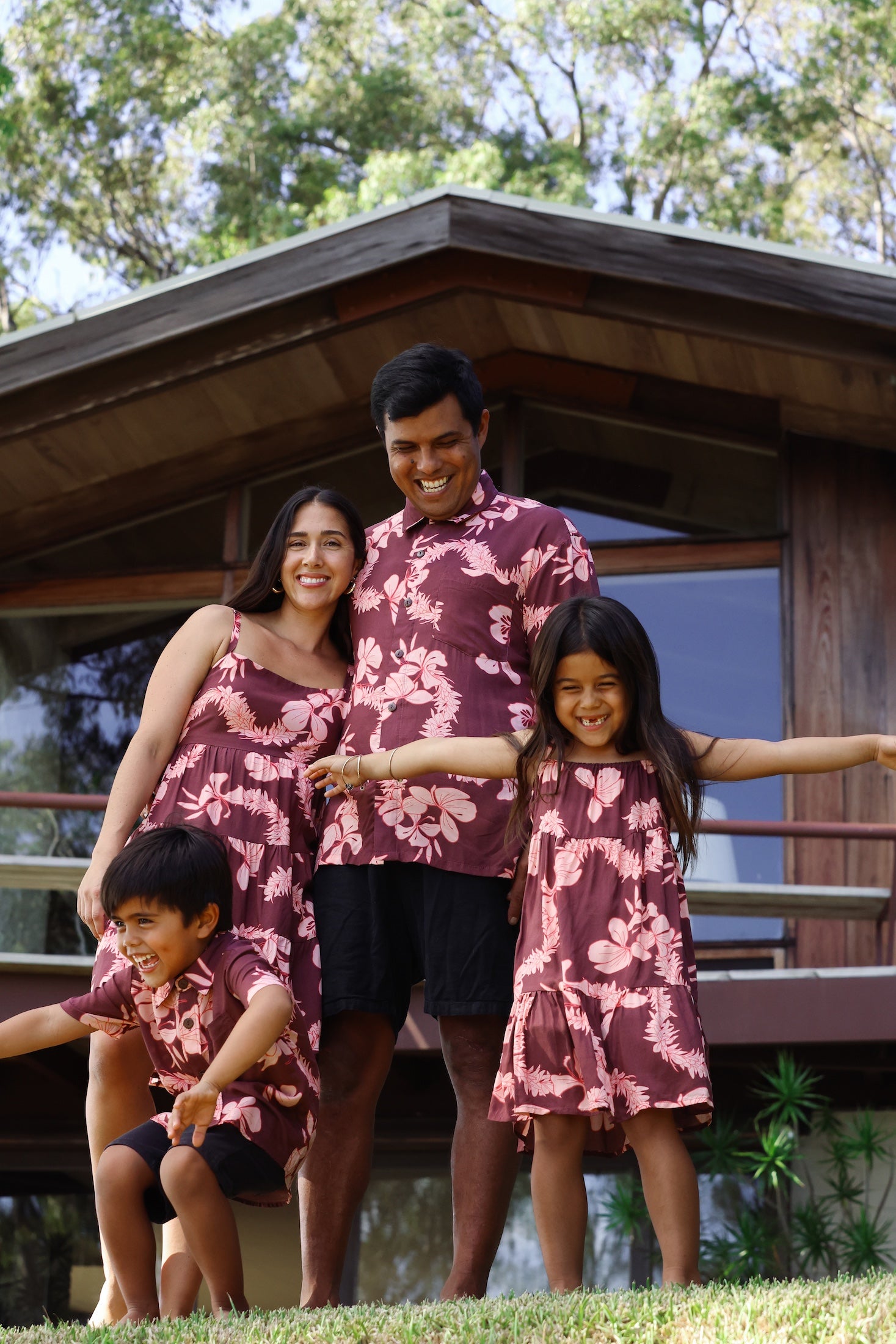 man wearing brown aloha shirt with pink lei awapuhi print