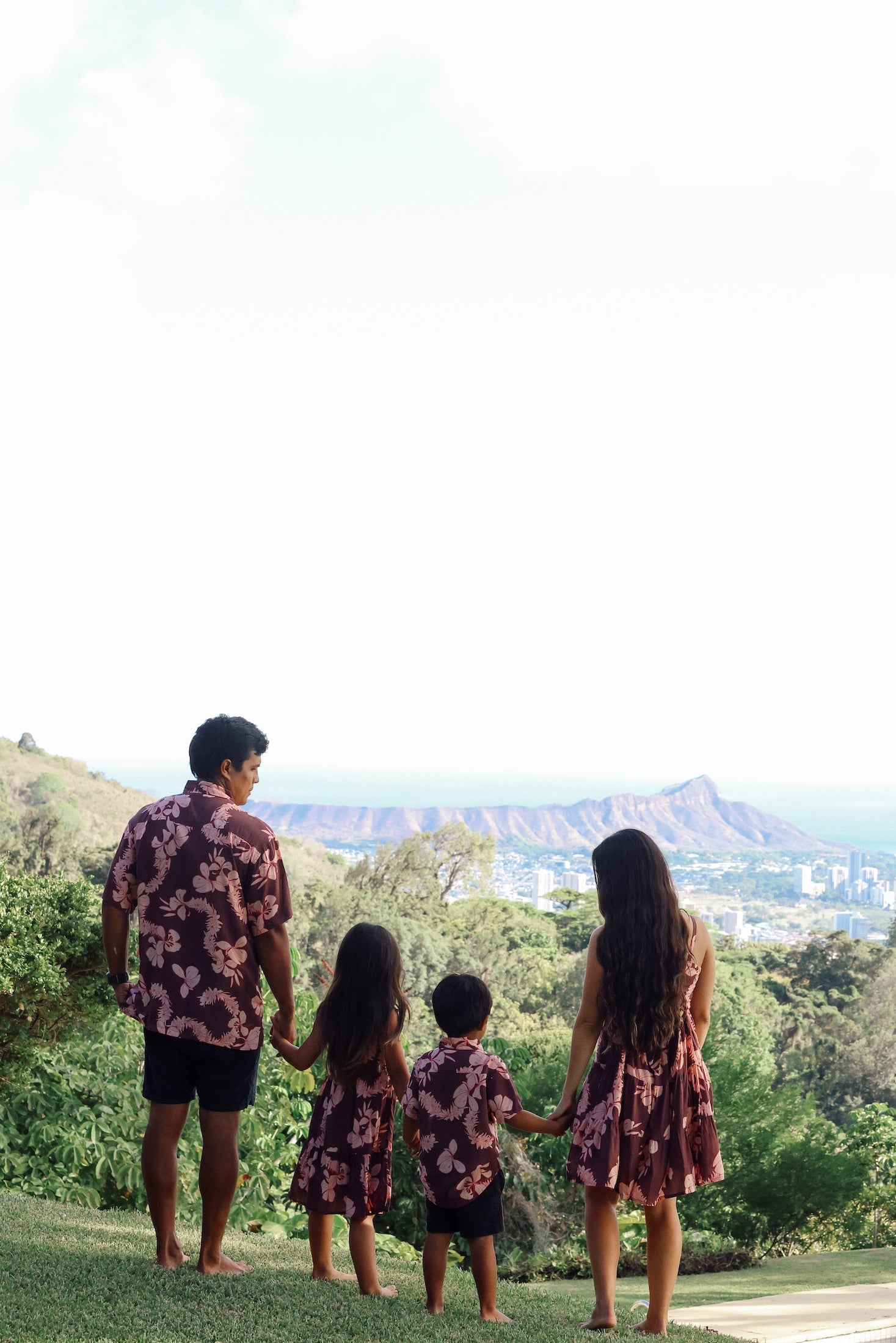 man wearing brown aloha shirt with pink lei awapuhi print