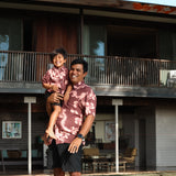 little boy wearing brown aloha shirt with pink lei awapuhi print