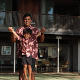 little boy wearing brown aloha shirt with pink lei awapuhi print