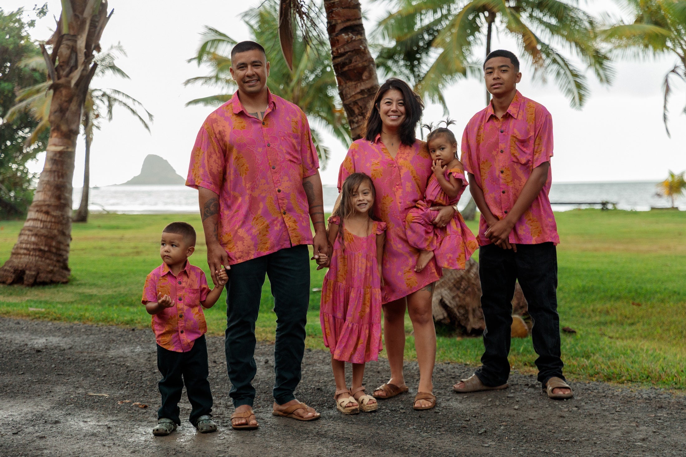 family wearing matching pink aloha wear with lei print