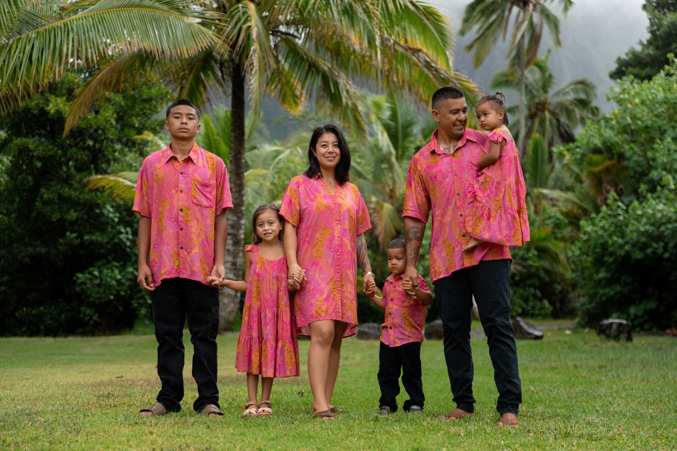 family wearing matching pink aloha wear with lei print