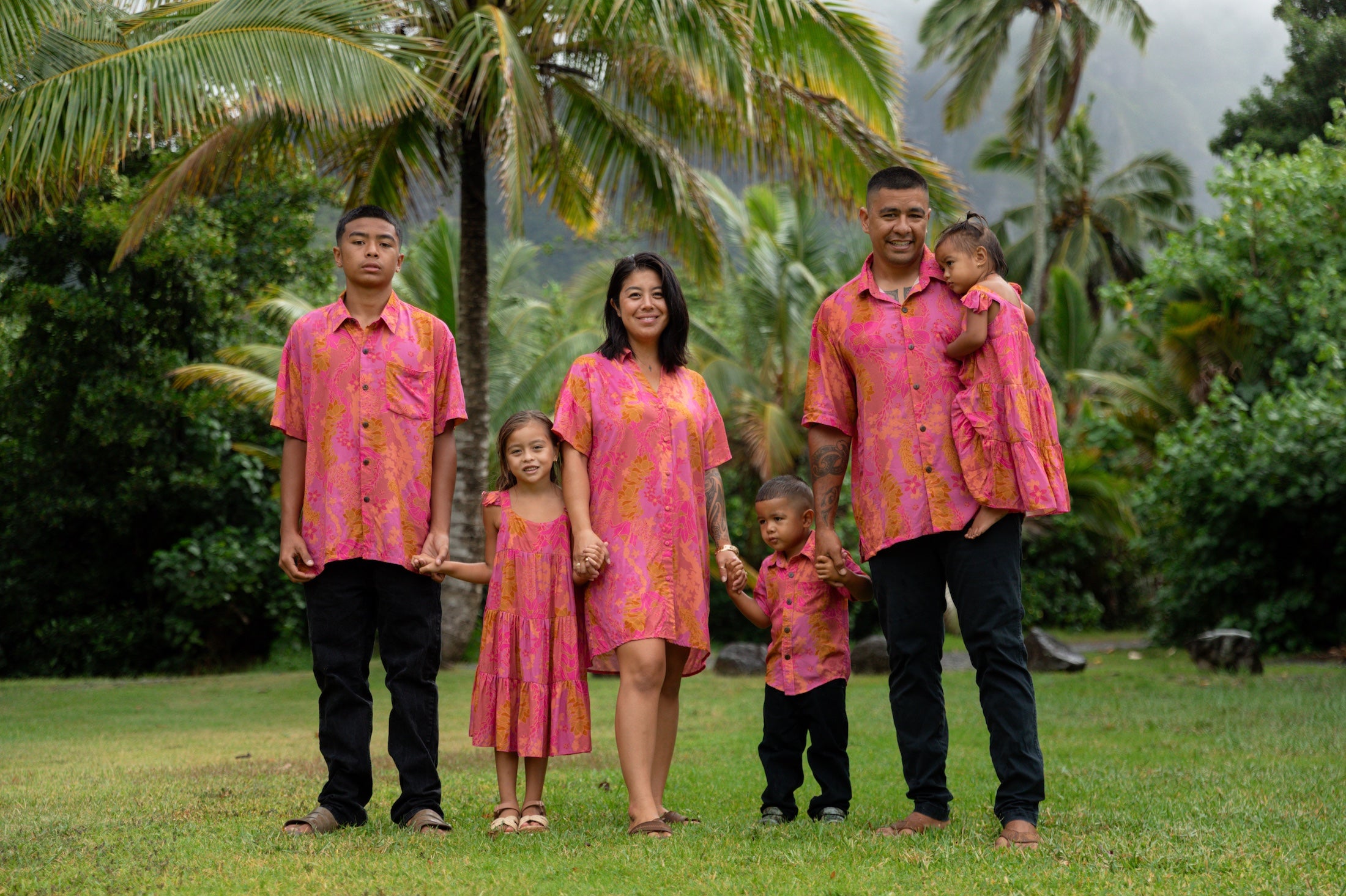 family wearing matching pink aloha wear with lei print