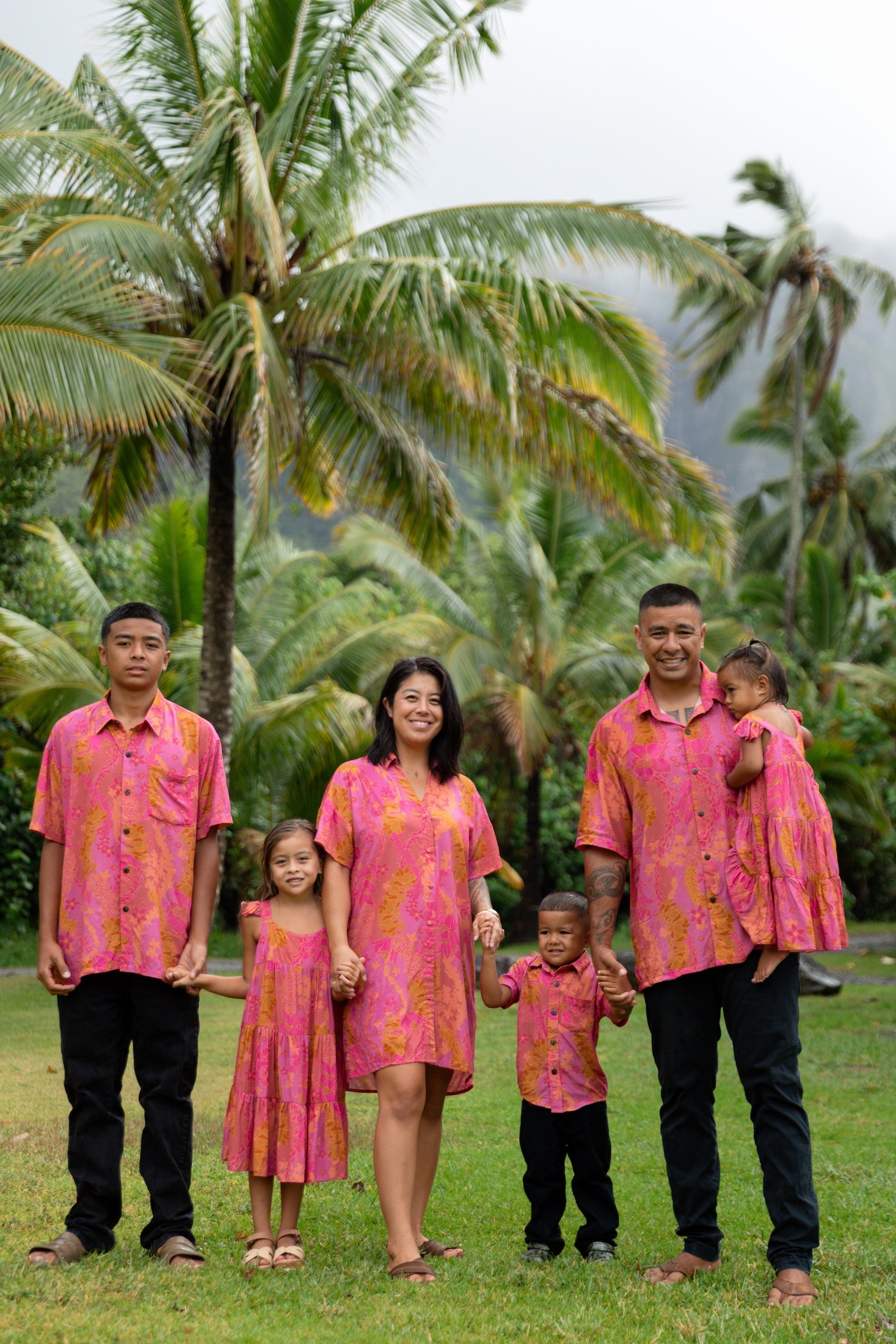 family wearing matching pink aloha wear with lei print