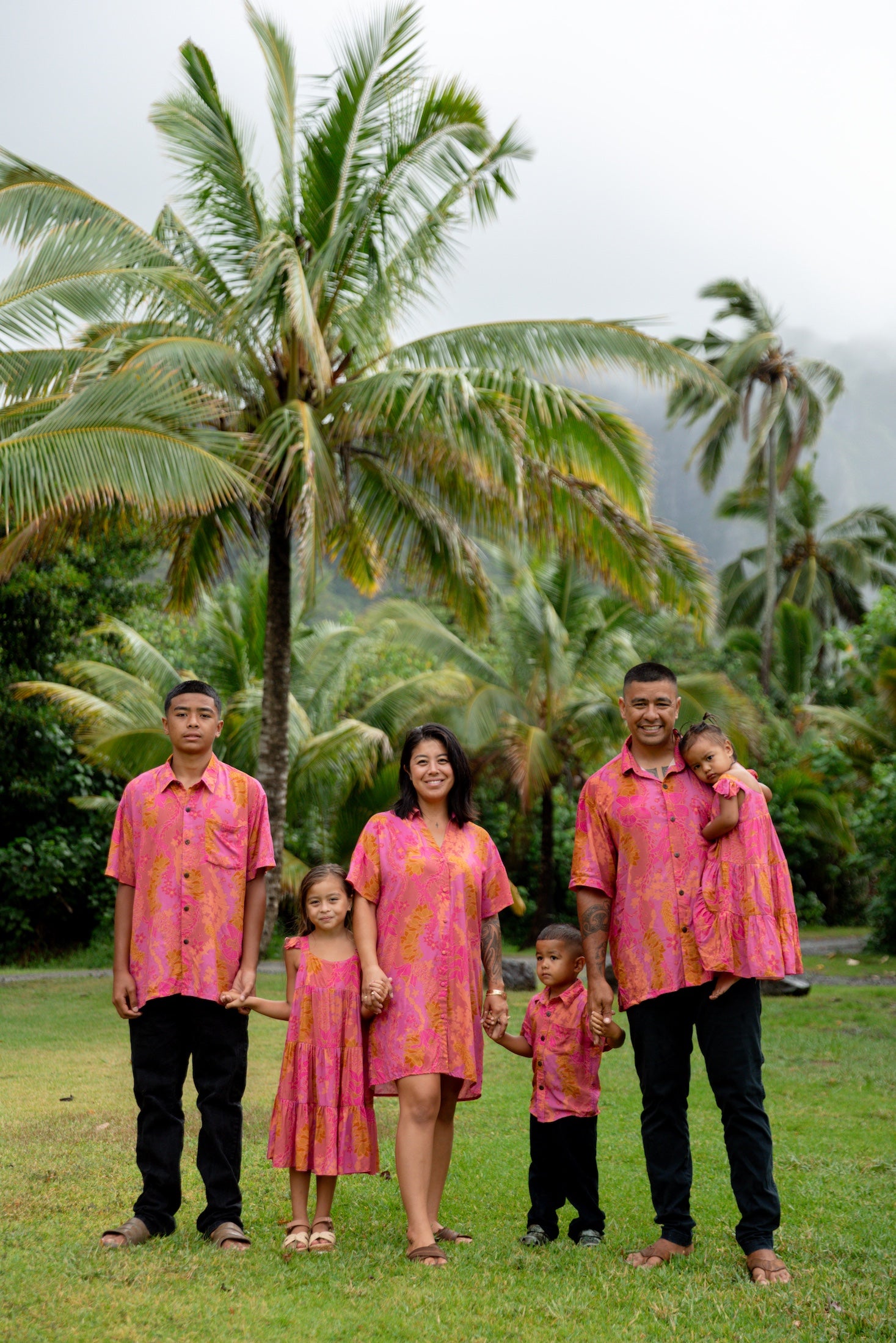 family wearing matching pink aloha wear with lei print