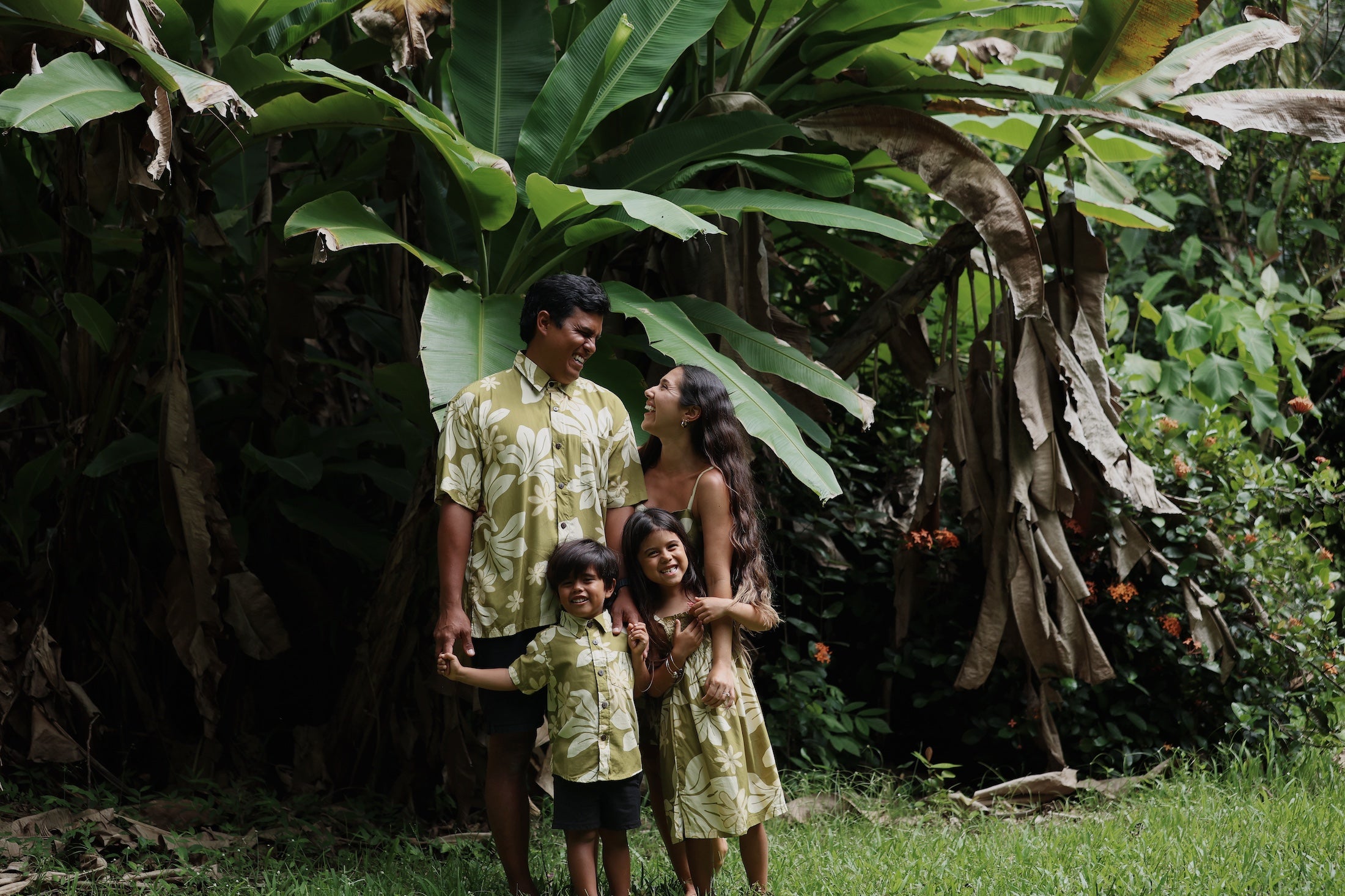 family wearing matching aloha wear in green print with naupaka pattern