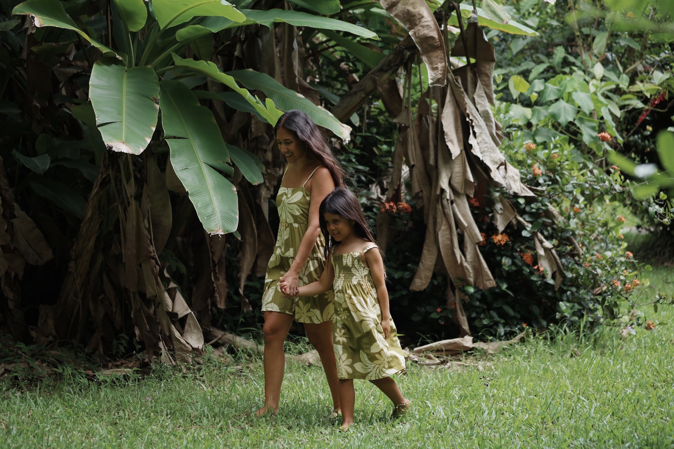 little girl wearing spaghetti strap dress in green print with naupaka pattern